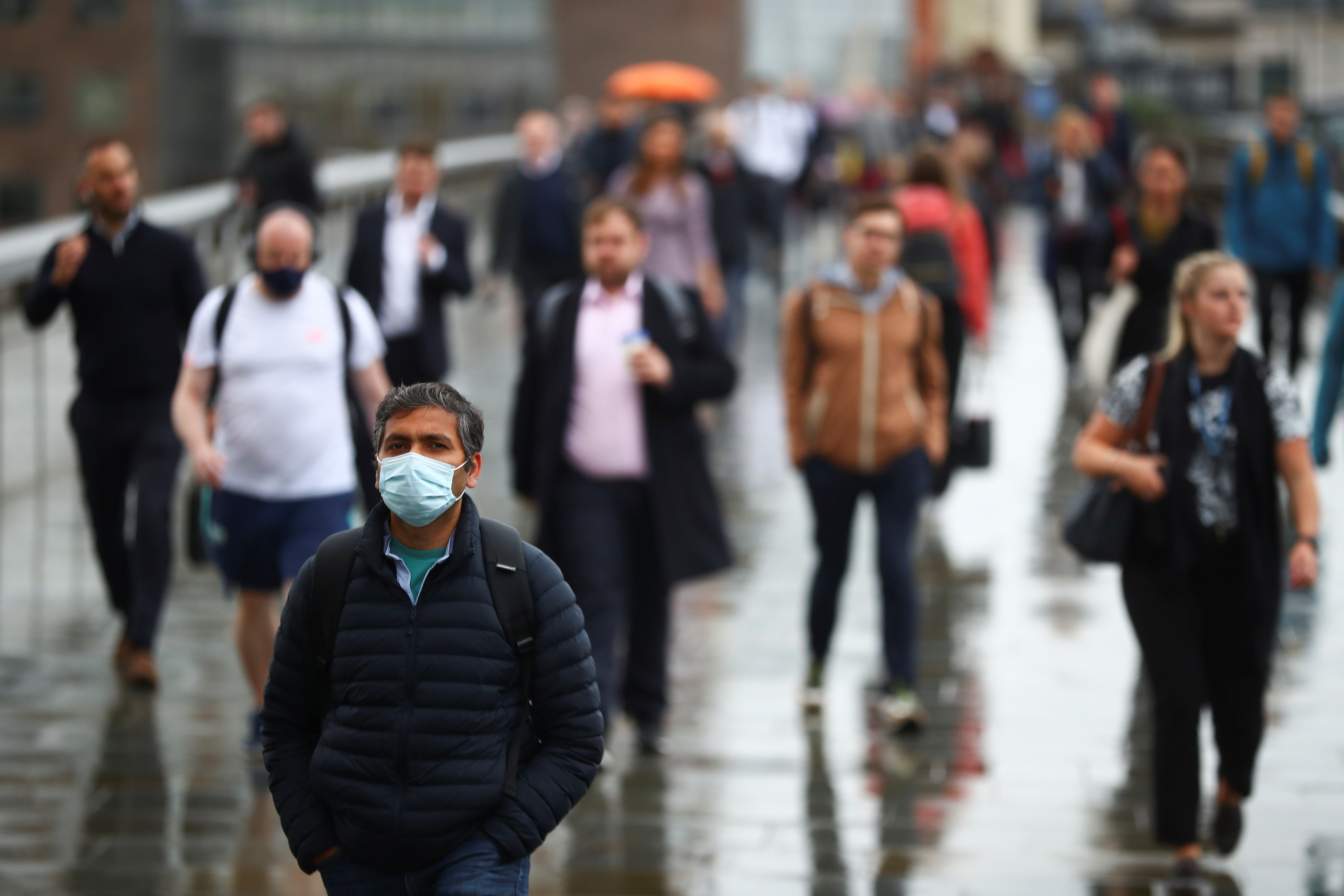 Commuters cross London Bridge in the rain. Almost nine in 10 adults in England are likely to have Covid antibodies, figures suggest