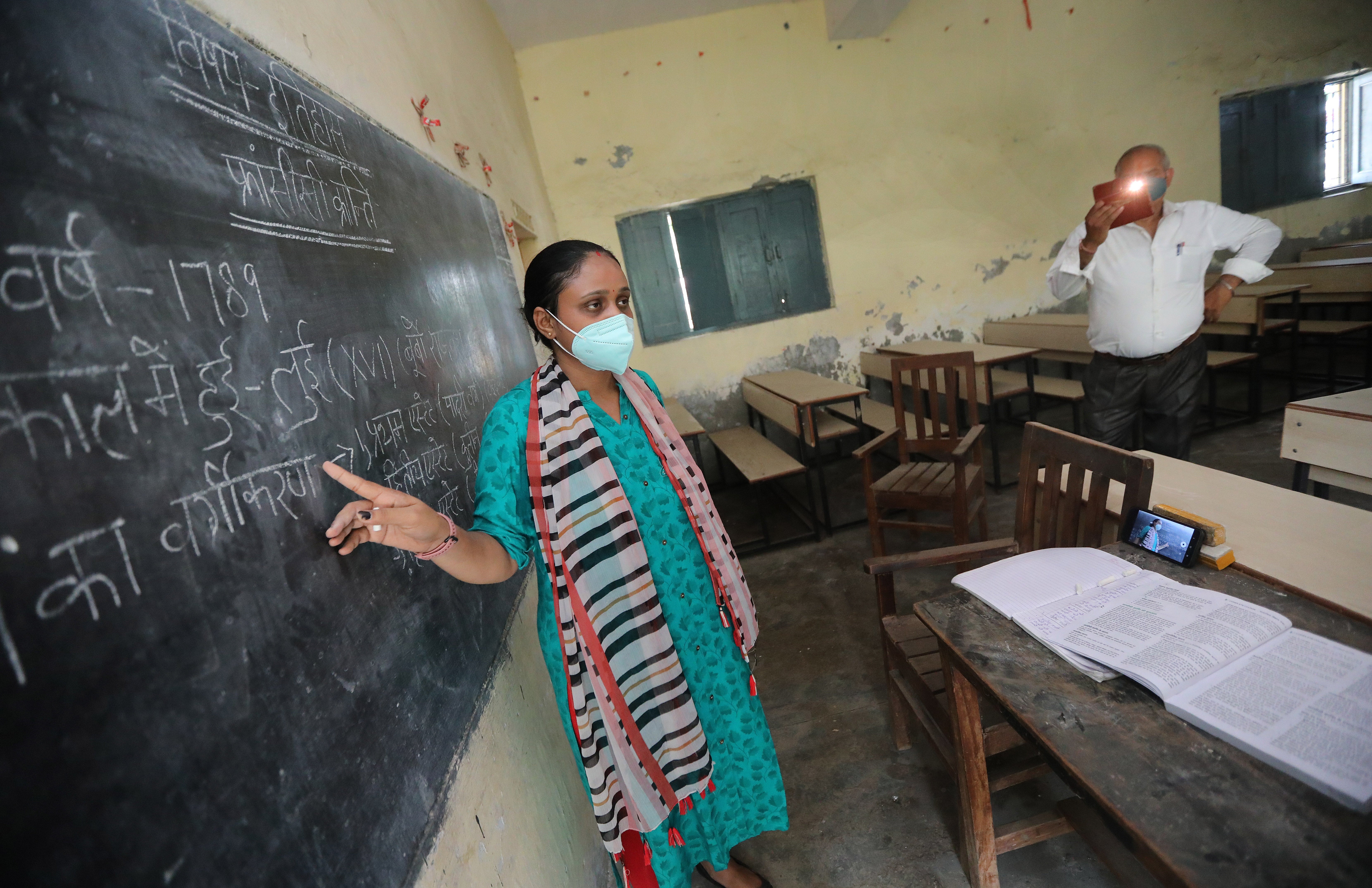 A teacher at Gandhi Smarak school in Raghunathpur near New Delhi records a history lesson via mobile phone for students