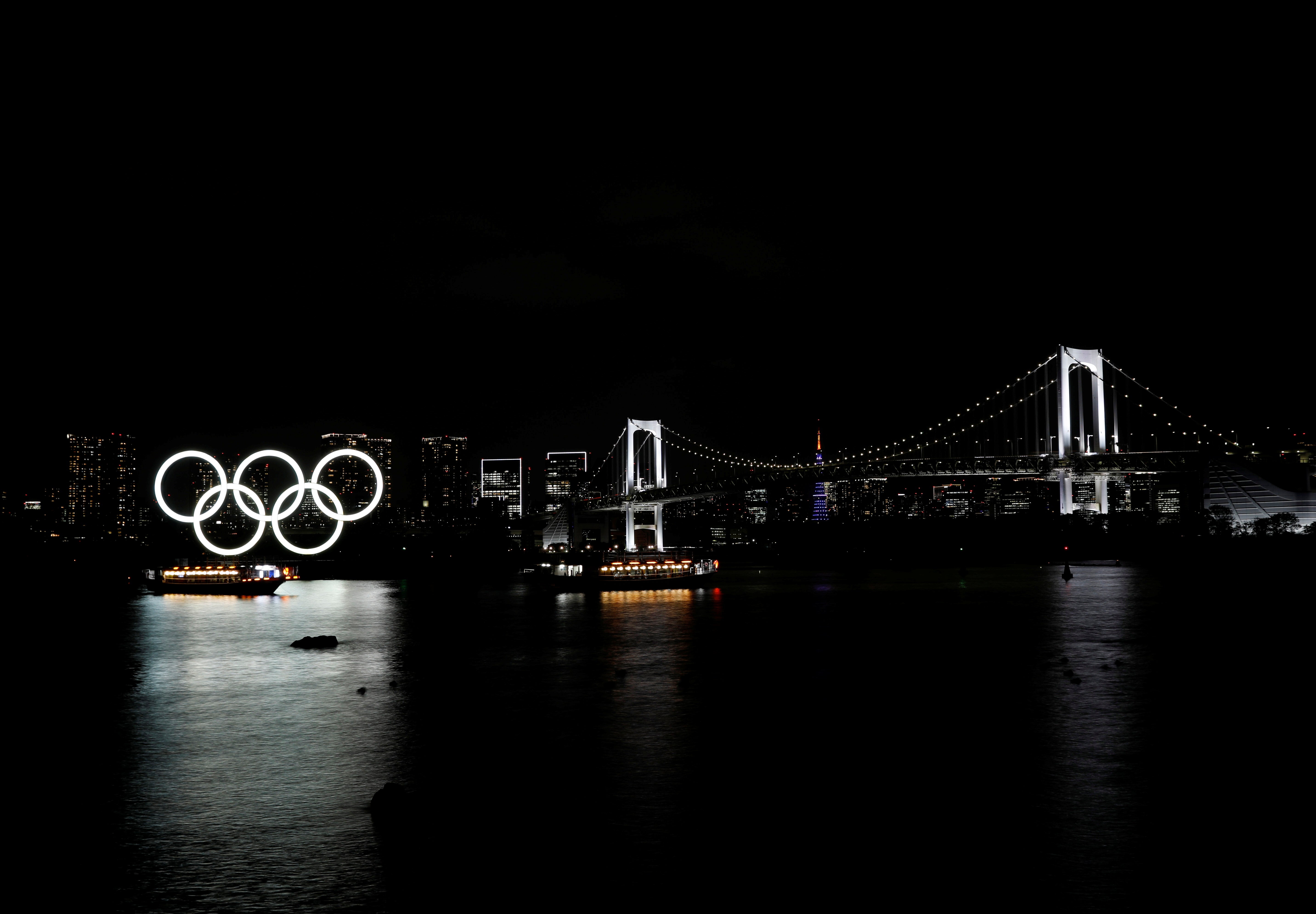 Boats sail past the giant Olympic rings and the Rainbow Bridge on the waterfront area of Odaiba Marine Park