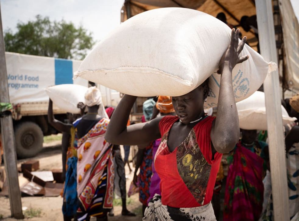 <p>Women from the Murle ethnic group carry bags of sorghum during a food distribution by United Nations World Food Programme in Gumuruk, South Sudan, 10 June. </p>