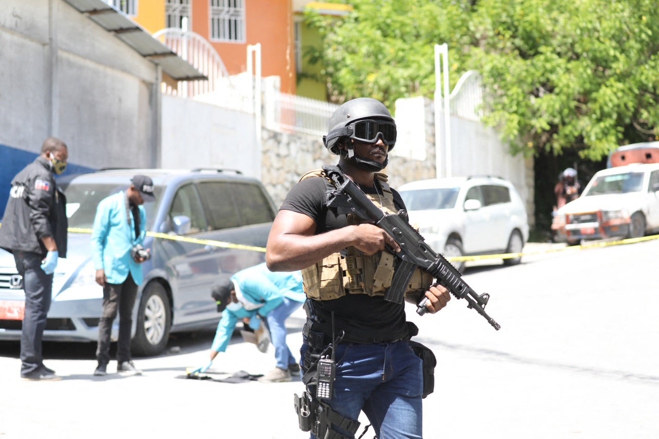 Members of the Haitian police and forensics look for evidence outside of the presidential residence