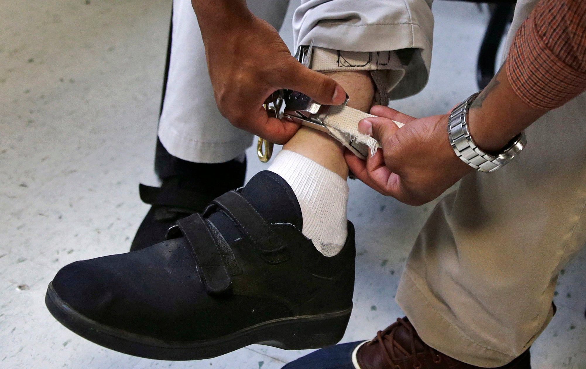 <p>Staff check the ankle strap of an electrical shocking device on a student during an exercise programme at the Judge Rotenberg Educational Center in Canton</p>