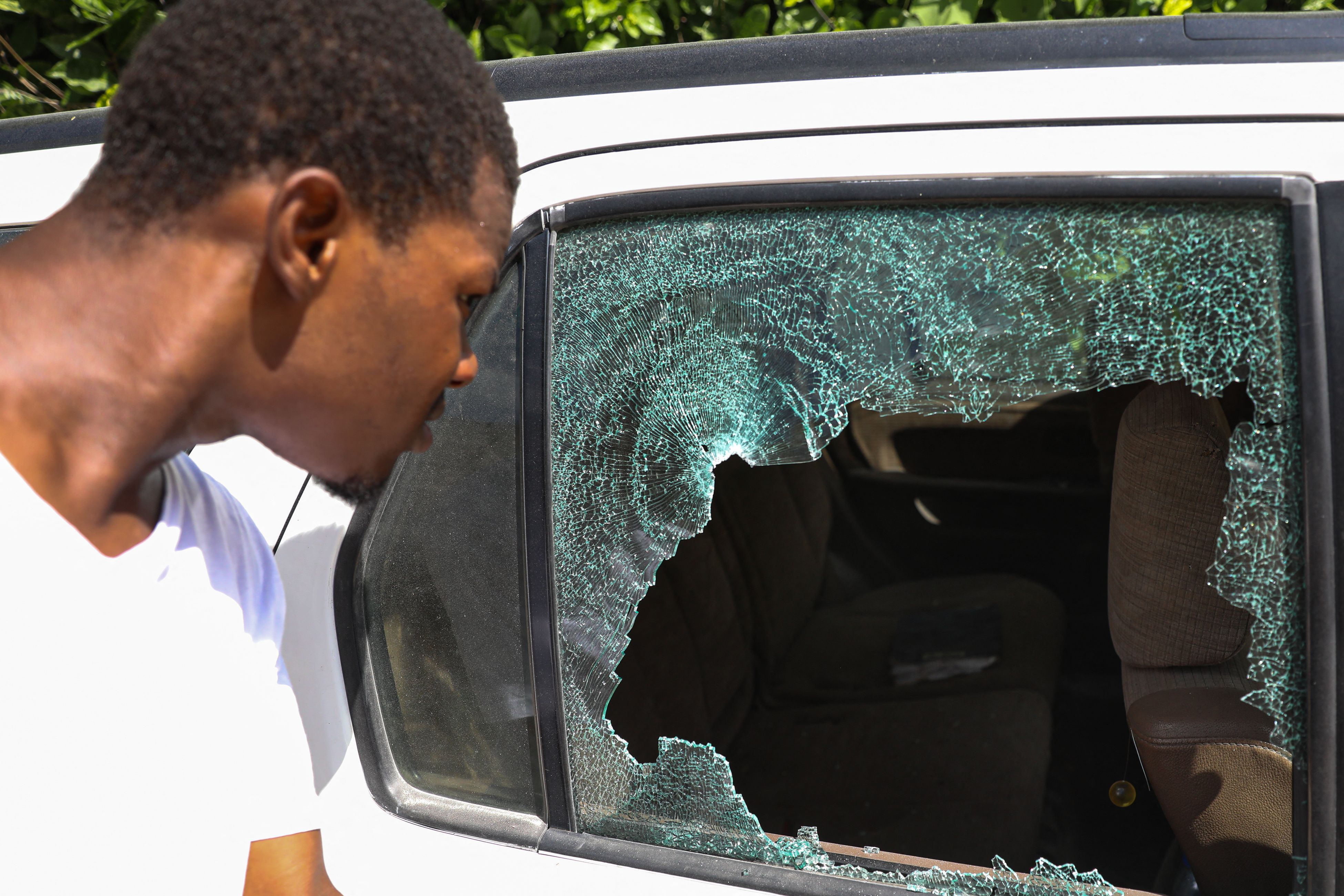 <p> A man looks at the bullet holes in a car outside of the presidential residence on July 7, 2021 in Port-au-Prince, Haiti.</p>