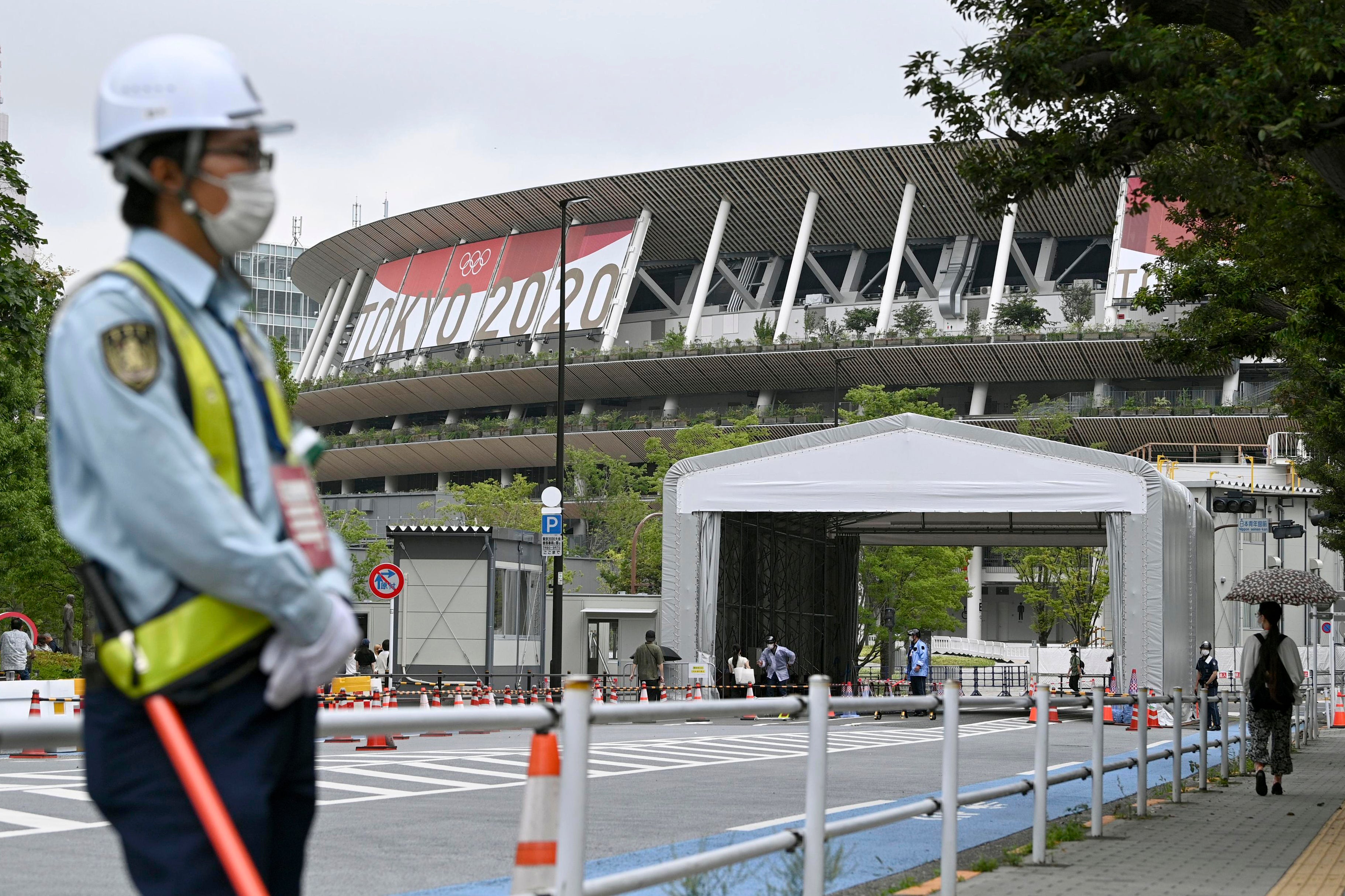 A security guard wearing a face mask guards the National Stadium in Tokyo