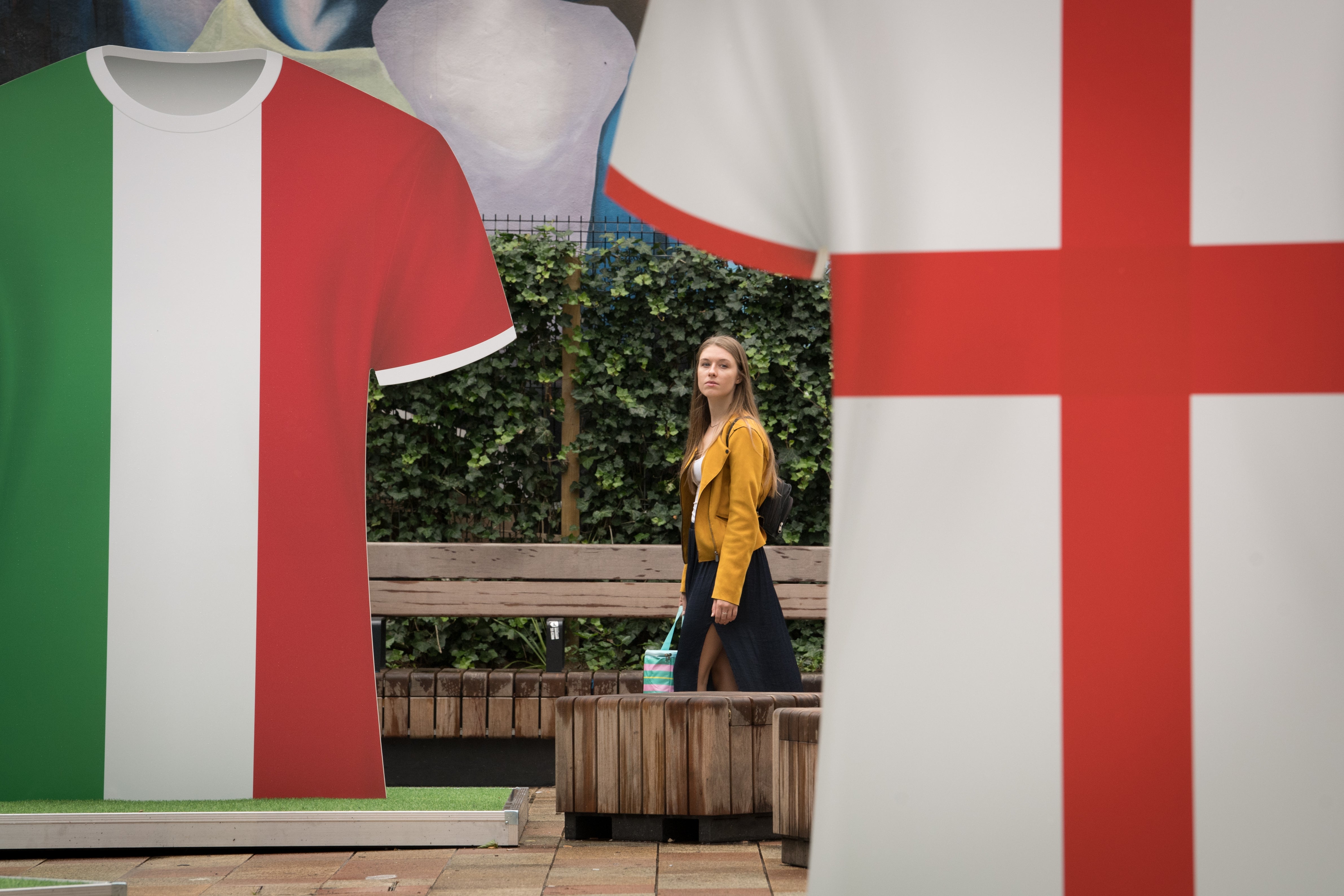 A woman walks past Italy and England football shirts