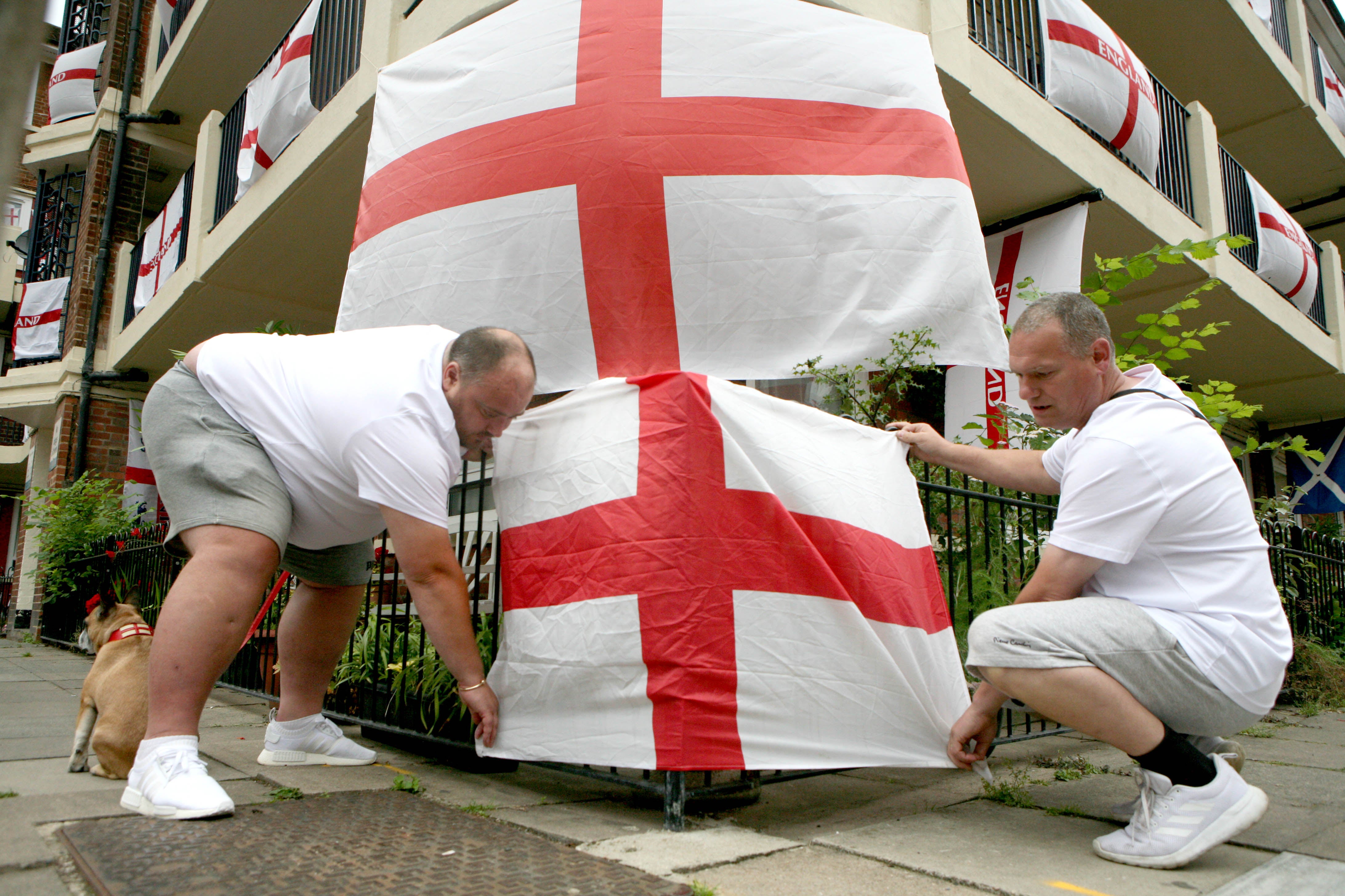 Chris Dowse (left) and Alan Putman, secure a flag on the Kirby Estate in Bermondsey, south London (Luciana Guerra/AP)