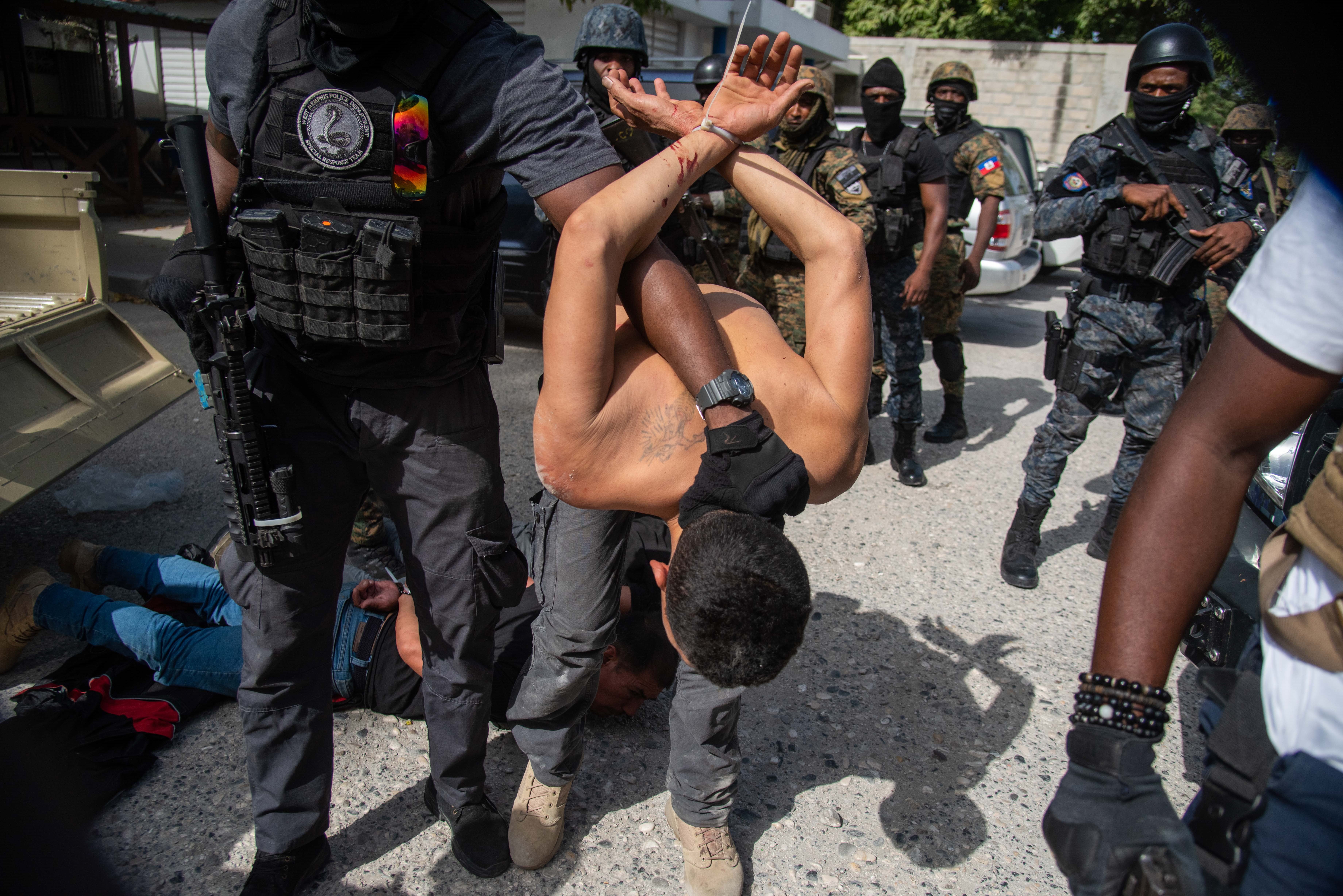 Police officers guard a group of suspects accused of having participated in the assassination of the Haitian president