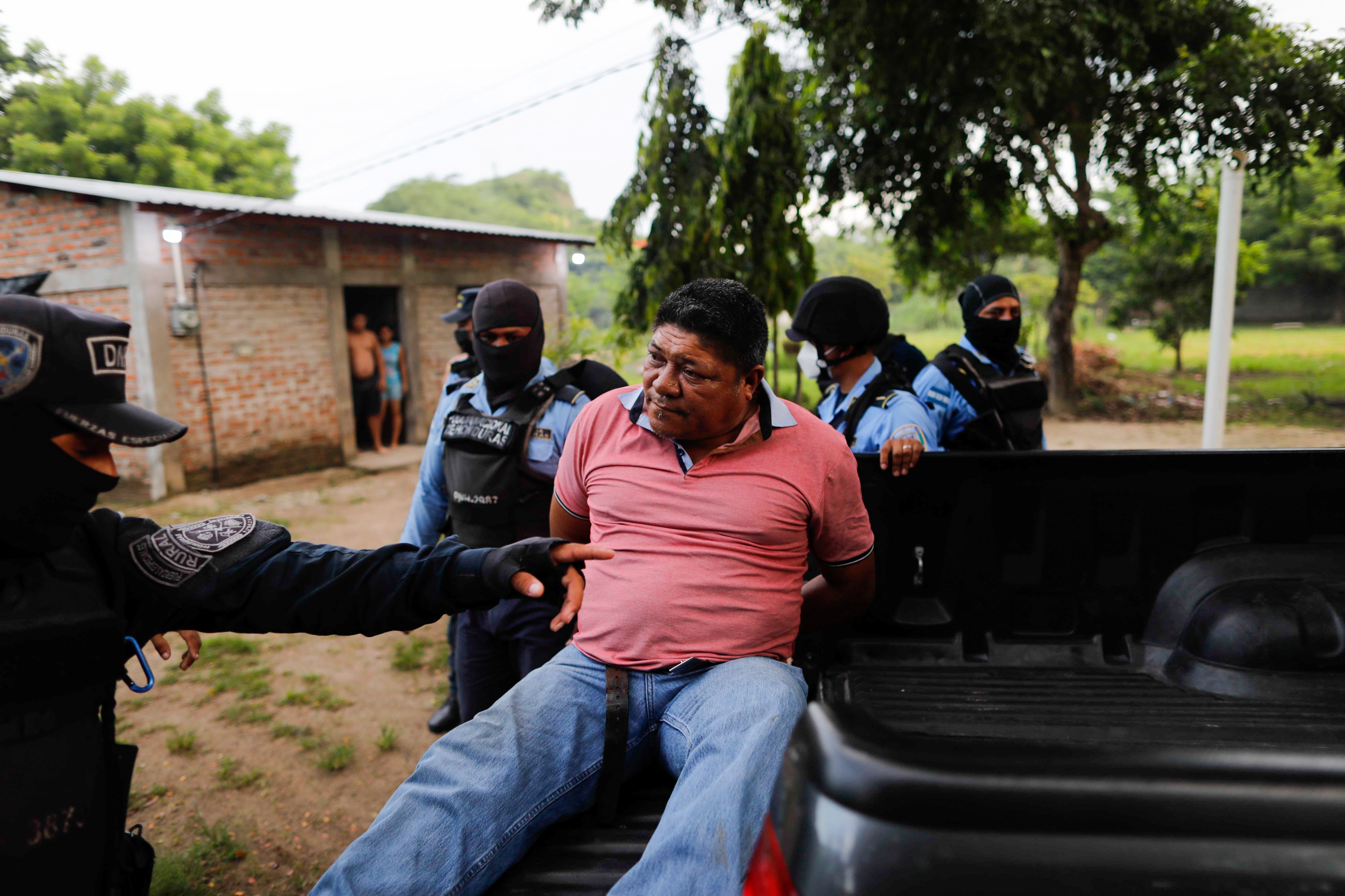 Honduran police officers detain a man on suspicion for his role in killing Giorgio Scanu, 65, who was lynched by a mob of more than 600 villagers in revenge for allegedly murdering a homeless man