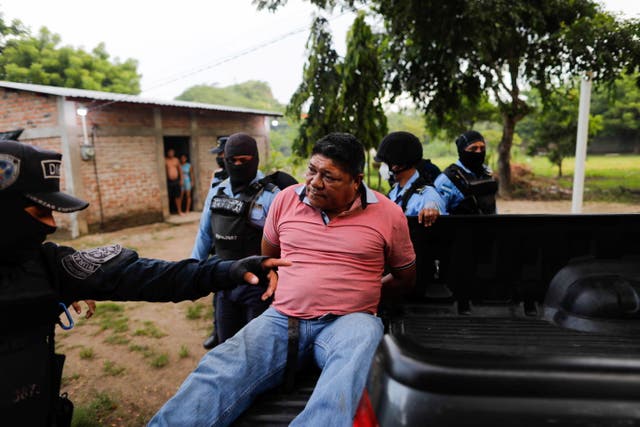 <p>Honduran police officers detain a man on suspicion for his role in killing Giorgio Scanu, 65, who was lynched by a mob of more than 600 villagers in revenge for allegedly murdering a homeless man</p>