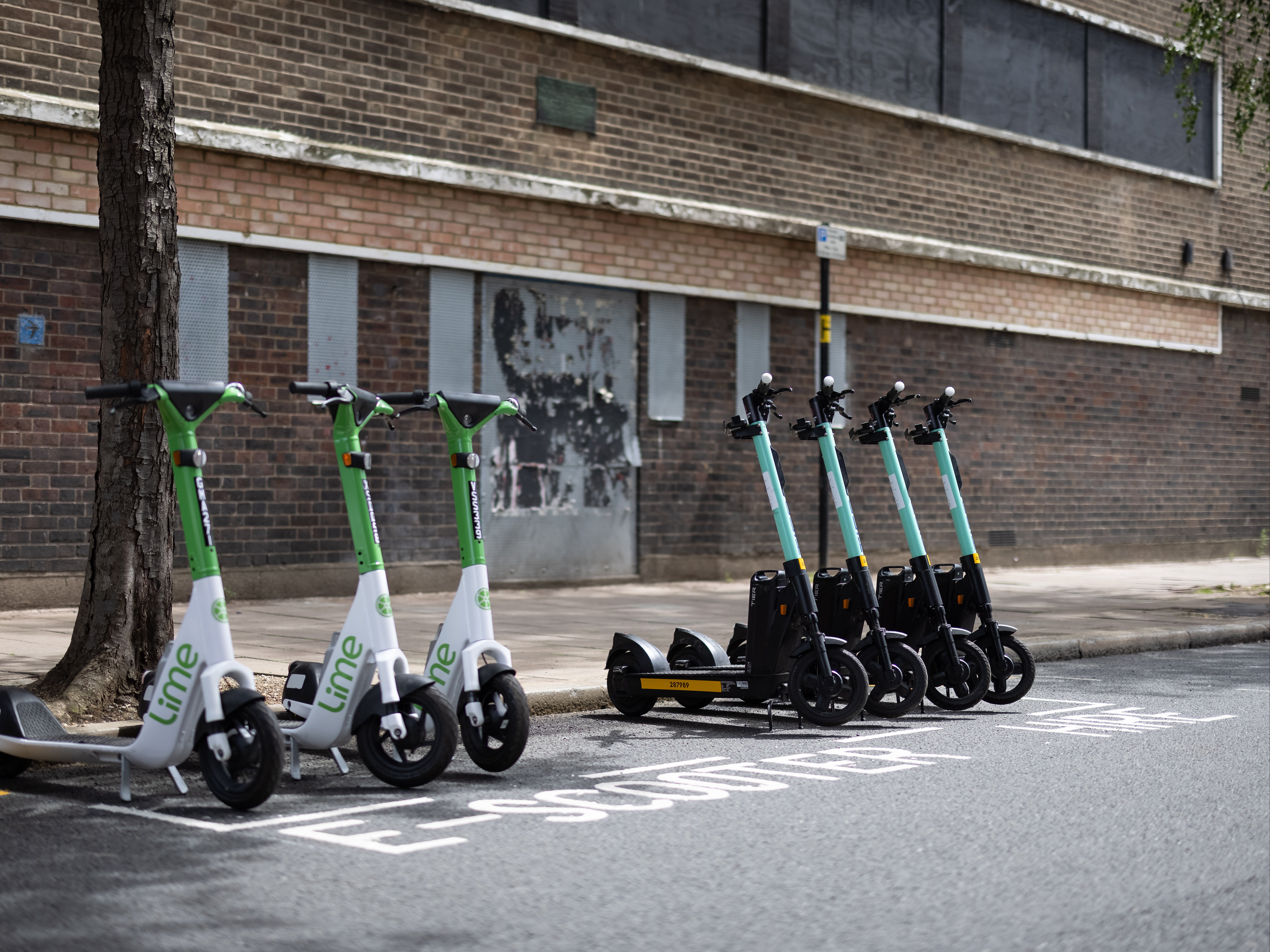 A row of both Lime (L) and Tier (R) electric scooters are seen in a parking bay on July 05, 2021 in London, England.