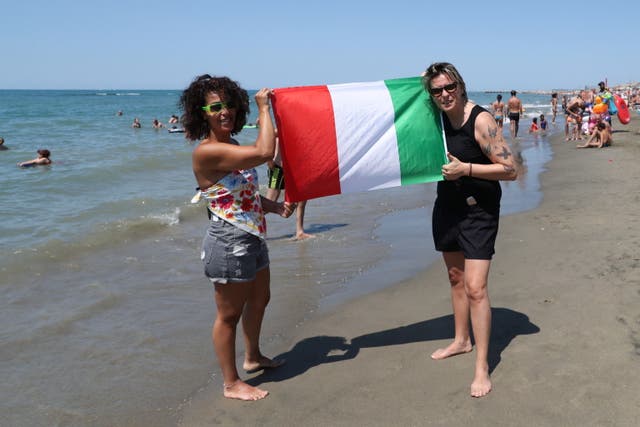 <p>Italian fans on the beaches of the Roman coast waving flags and tricolor scarves ahead of the final</p>