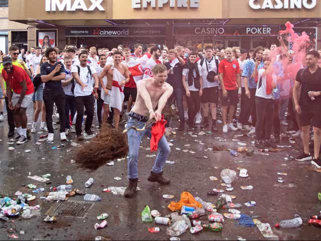 <p>A fan throws a decorative tree which has been uprooted from Leicester Square</p>