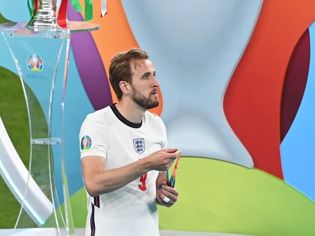 <p>Harry Kane walks past the European Championship trophy after removing his runners-up medal</p>