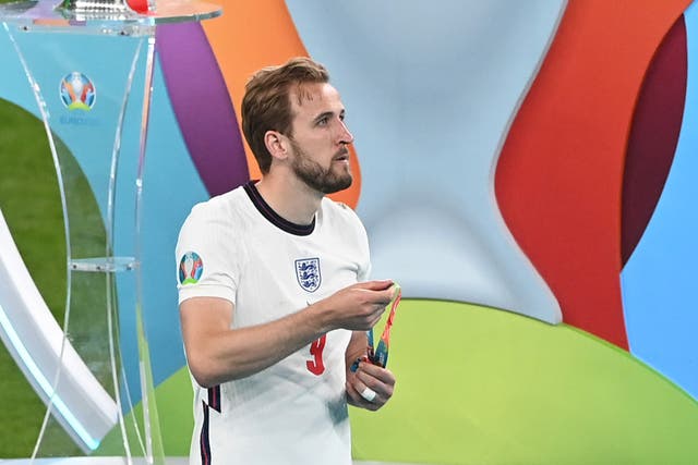 <p>Harry Kane walks past the European Championship trophy after removing his runners-up medal</p>