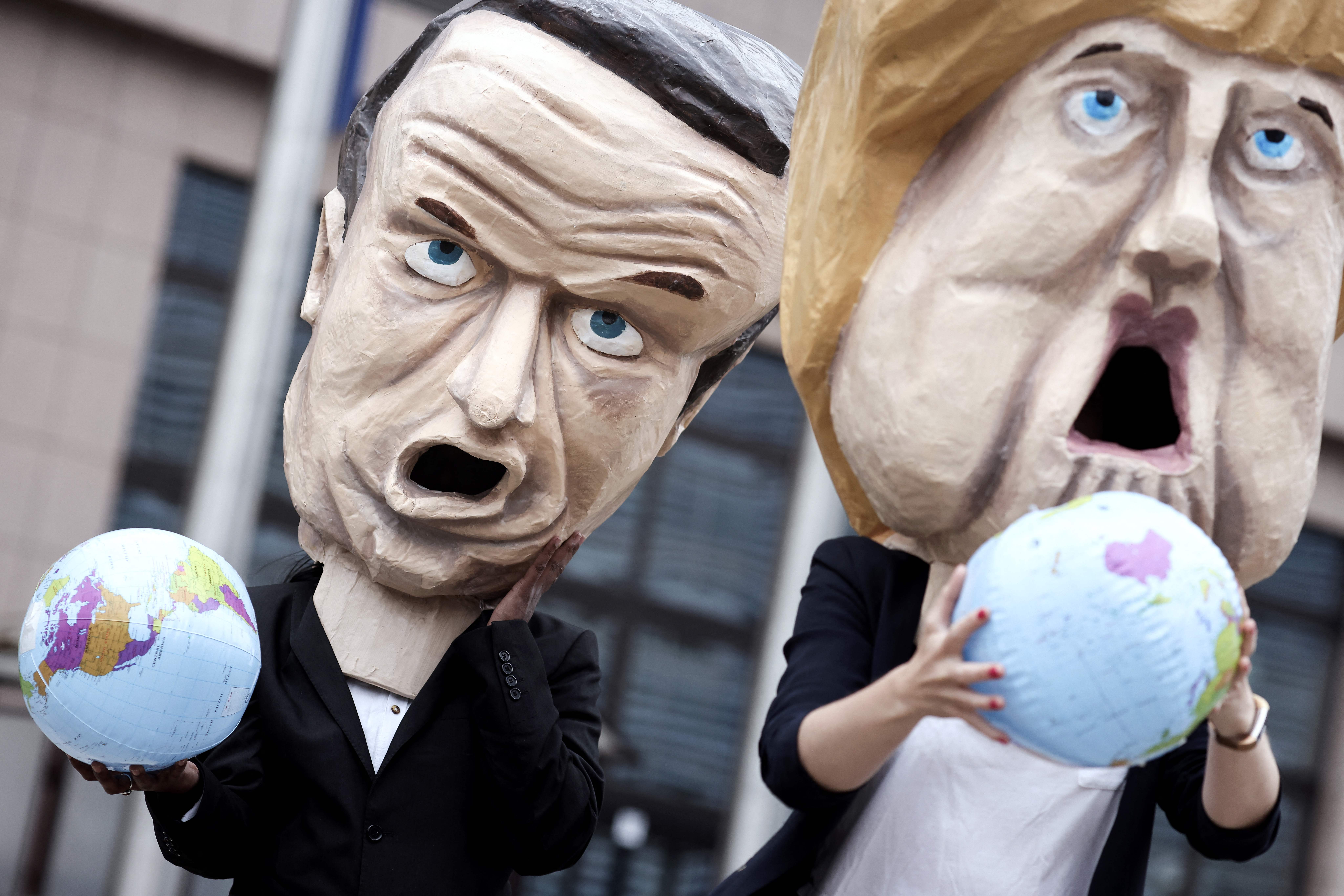 Environmental activists mimicking EU leaders Emmanuel Macron and Merkel outside the European Council building in Brussels on 6 July 2021