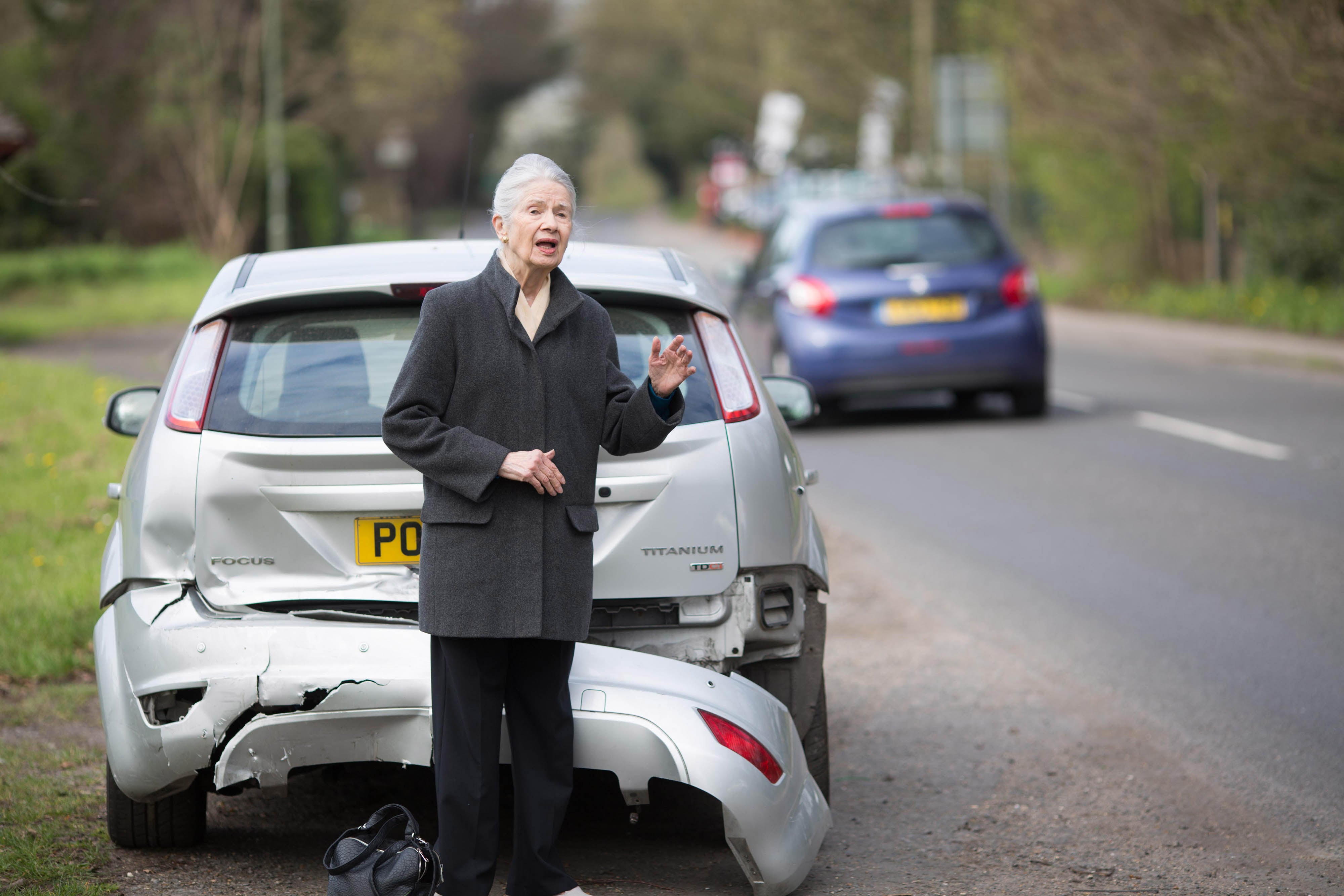 A woman waiting beside a damaged car