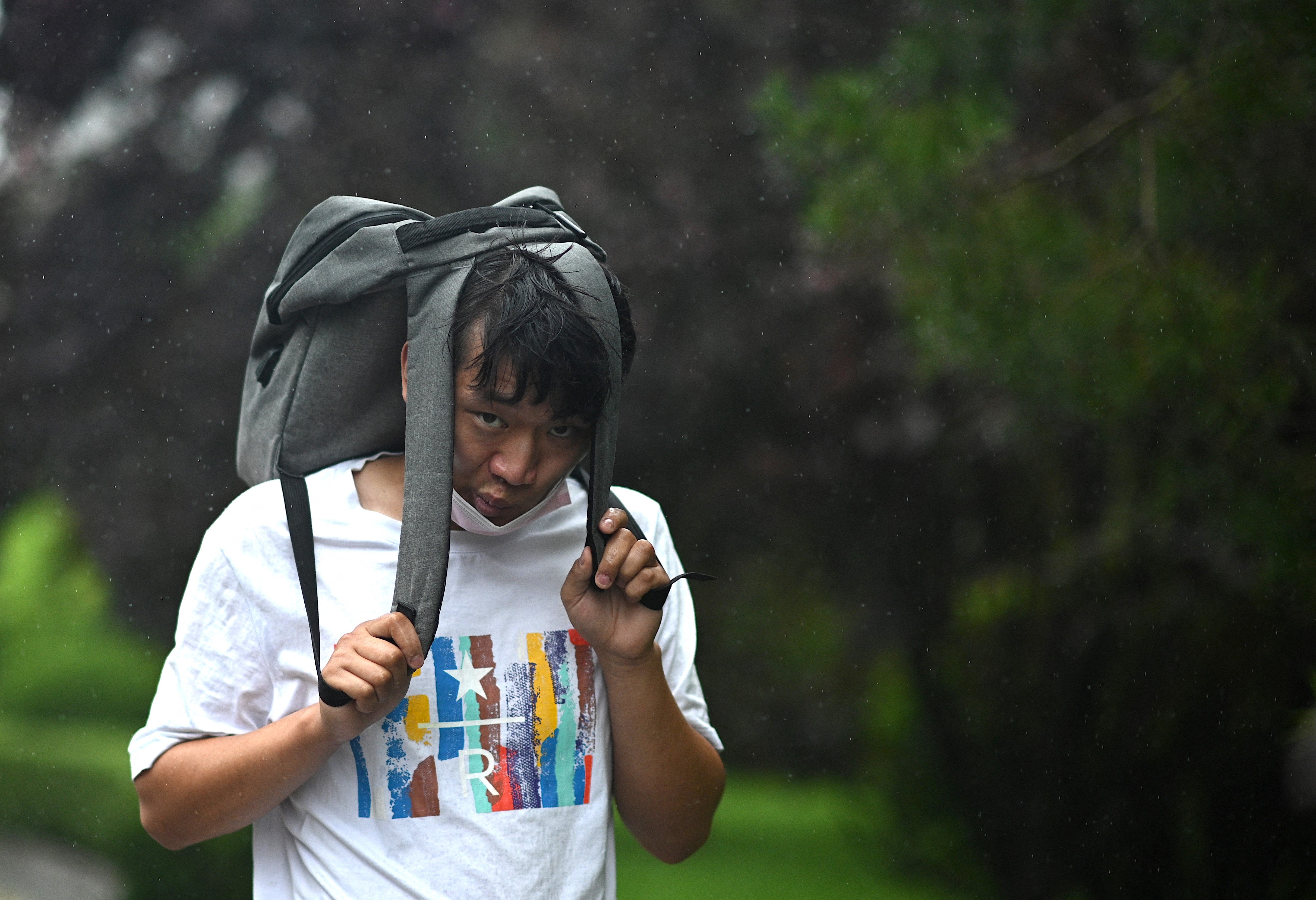 A man uses his bag as cover during a storm in Beijing