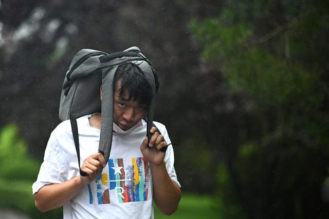 <p>A man uses his bag as cover during a storm in Beijing </p>