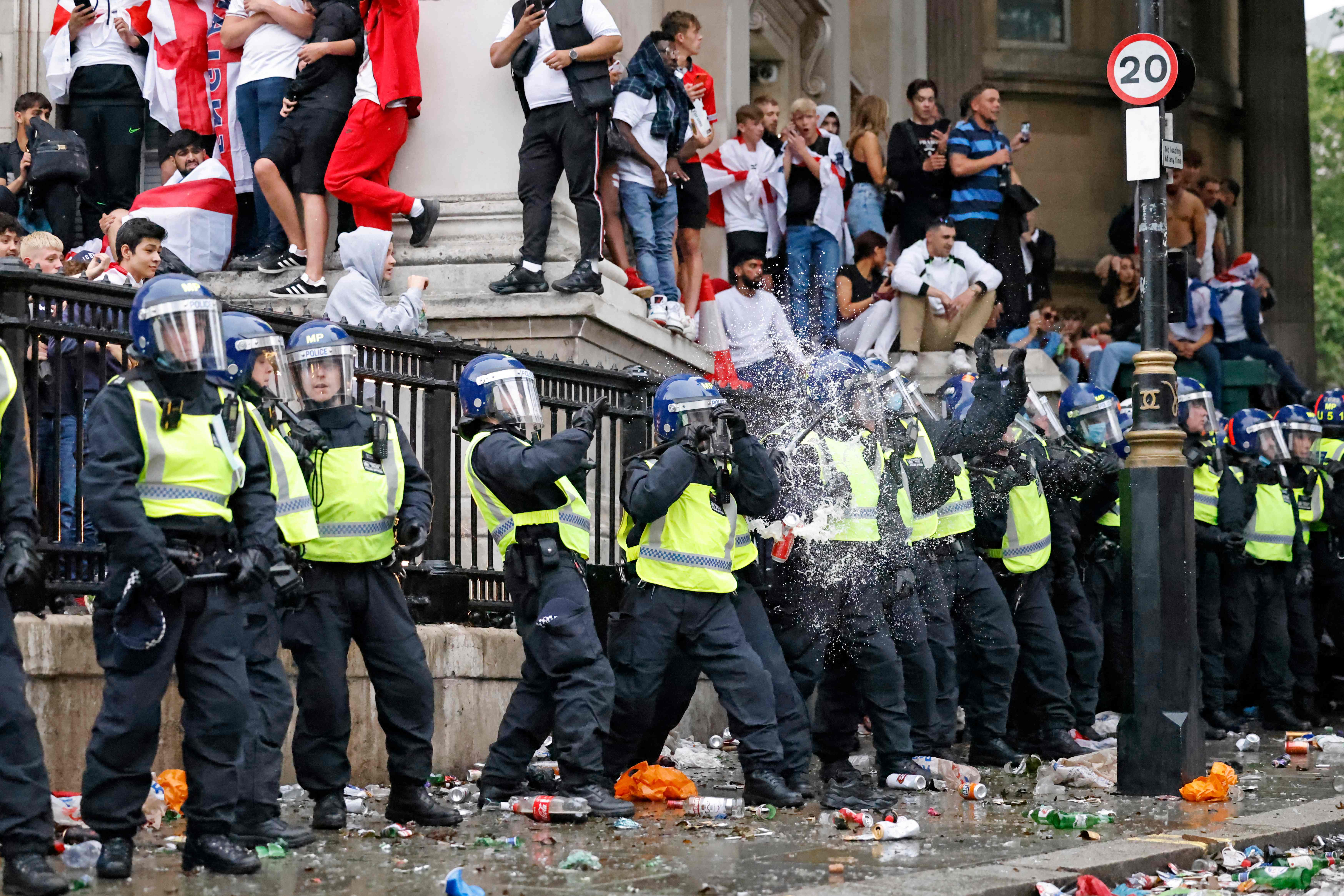 A line of police officers are the target of beer can throwers as England supporters stand around the edges of Trafalgar Square during a live screening of the UEFA Euro 2020 final football match between England and Italy in central London on 11 July, 2021.