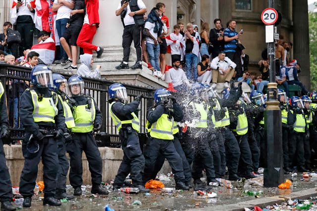 <p>A line of police officers are the target of beer can throwers as England supporters stand around the edges of Trafalgar Square during a live screening of the UEFA Euro 2020 final football match between England and Italy in central London on 11 July, 2021. </p>
