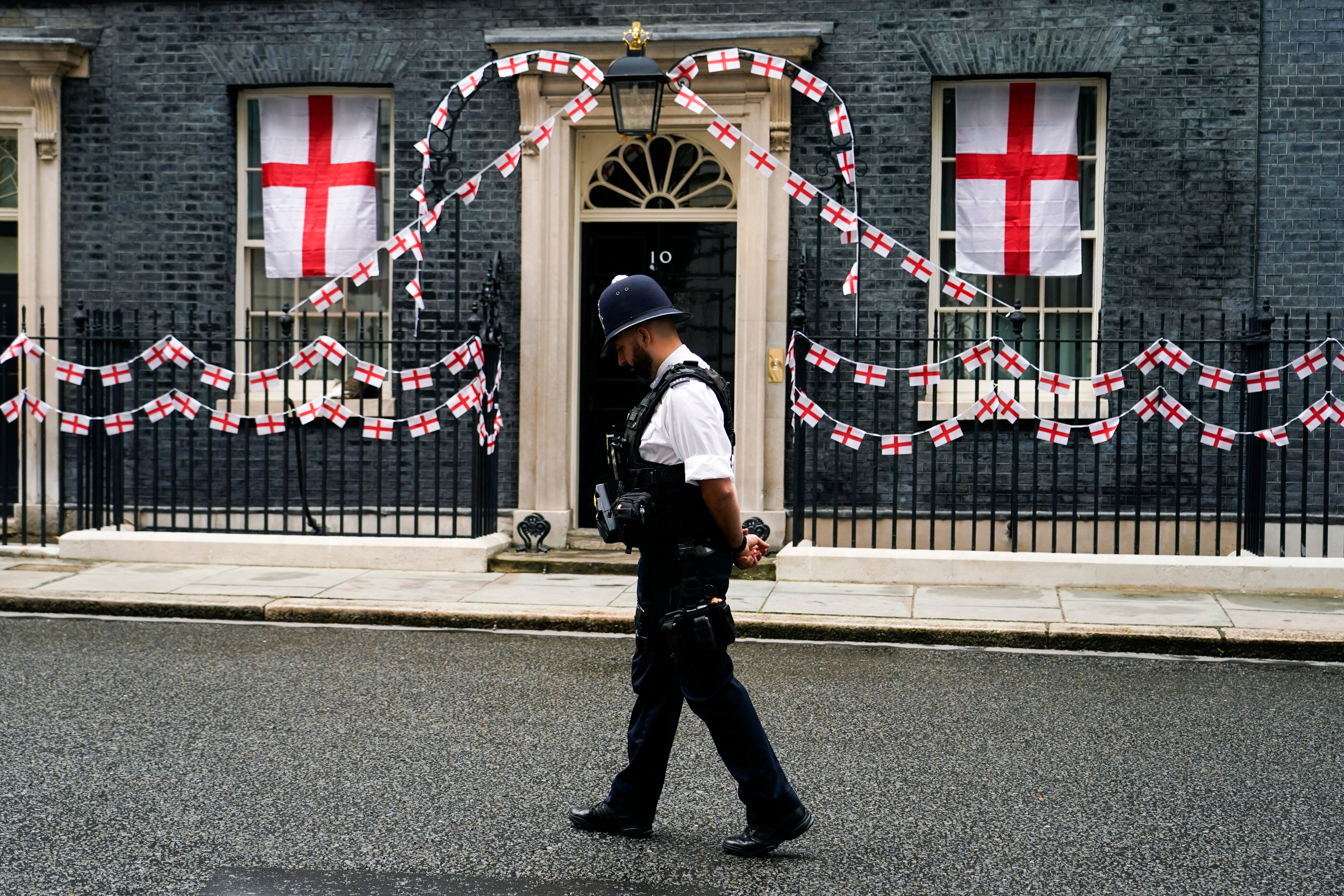 A police officer walks past 10 Downing Street decorated with England flags