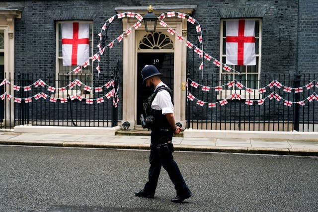 <p>A police officer walks past 10 Downing Street decorated with England flags</p>