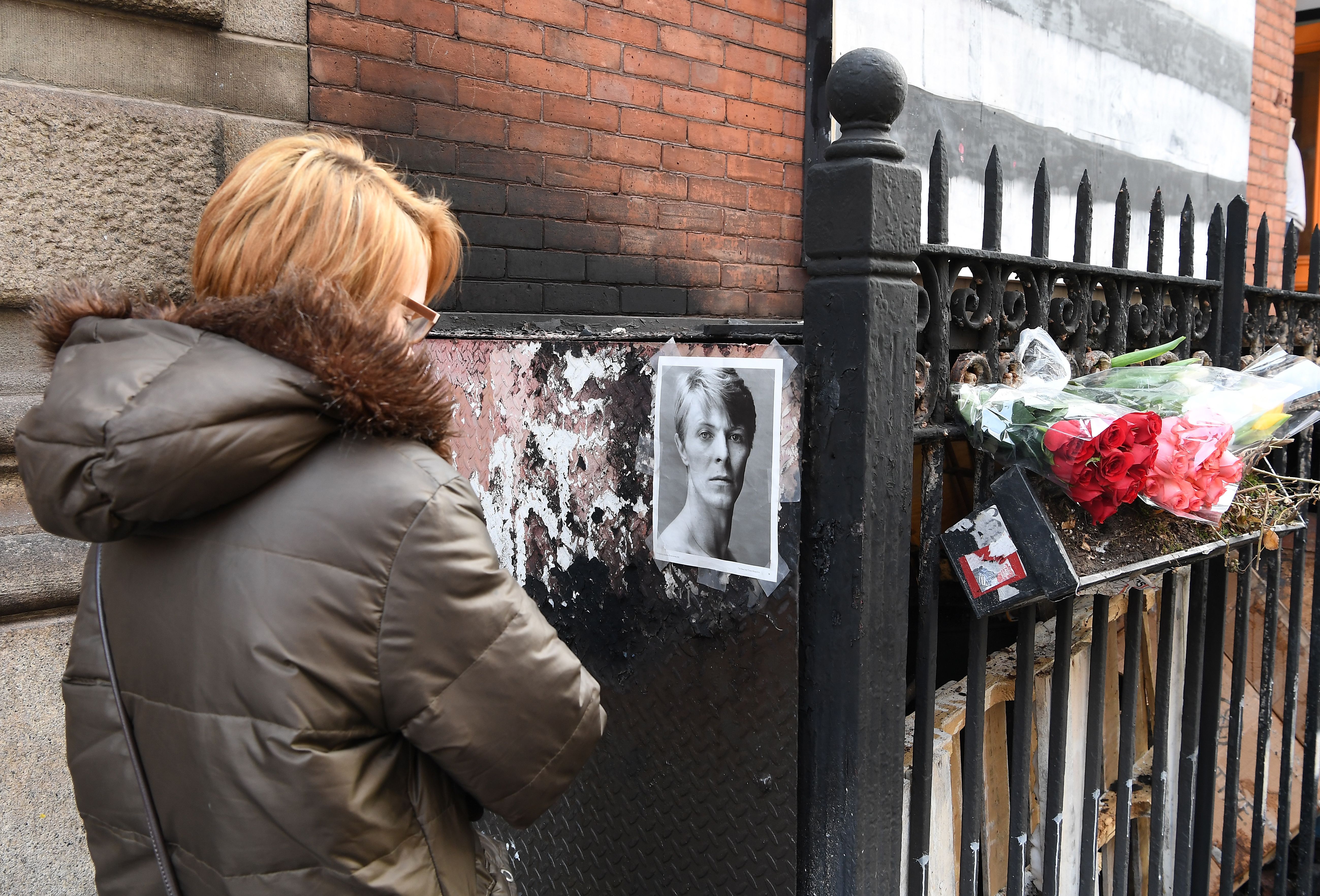 A woman pauses outside David Bowie’s SoHo apartment building on 10 January 2017, the first anniversary of the music icon’s death.