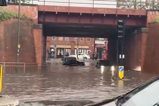 <p>Floodwaters submerge cars in Raynes Park, southwest London</p>