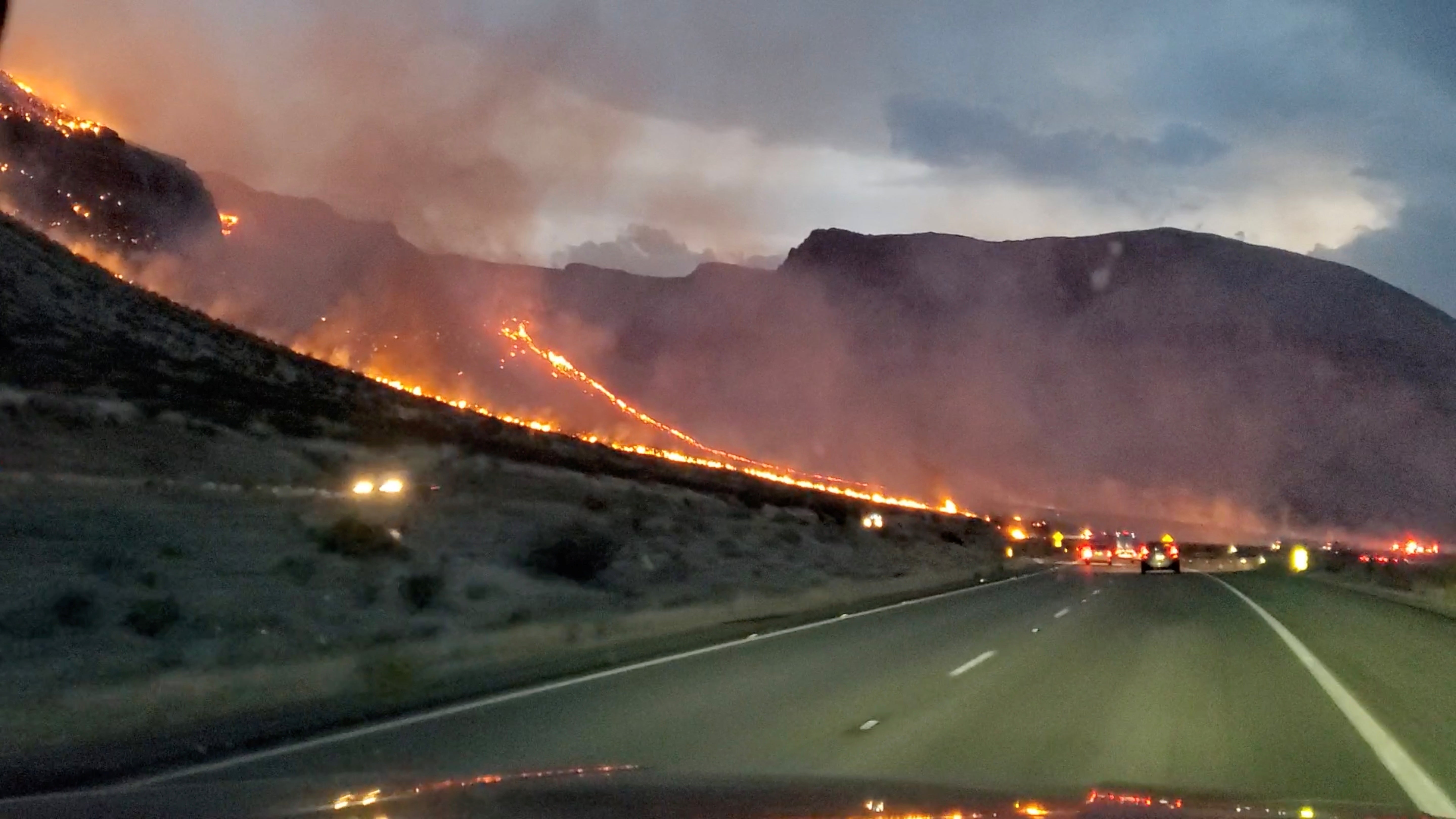 Flames are seen on side of the highway after a bushfire broke out, near St. George, Arizona on 12 July 2021, in this still image obtained from a social media video