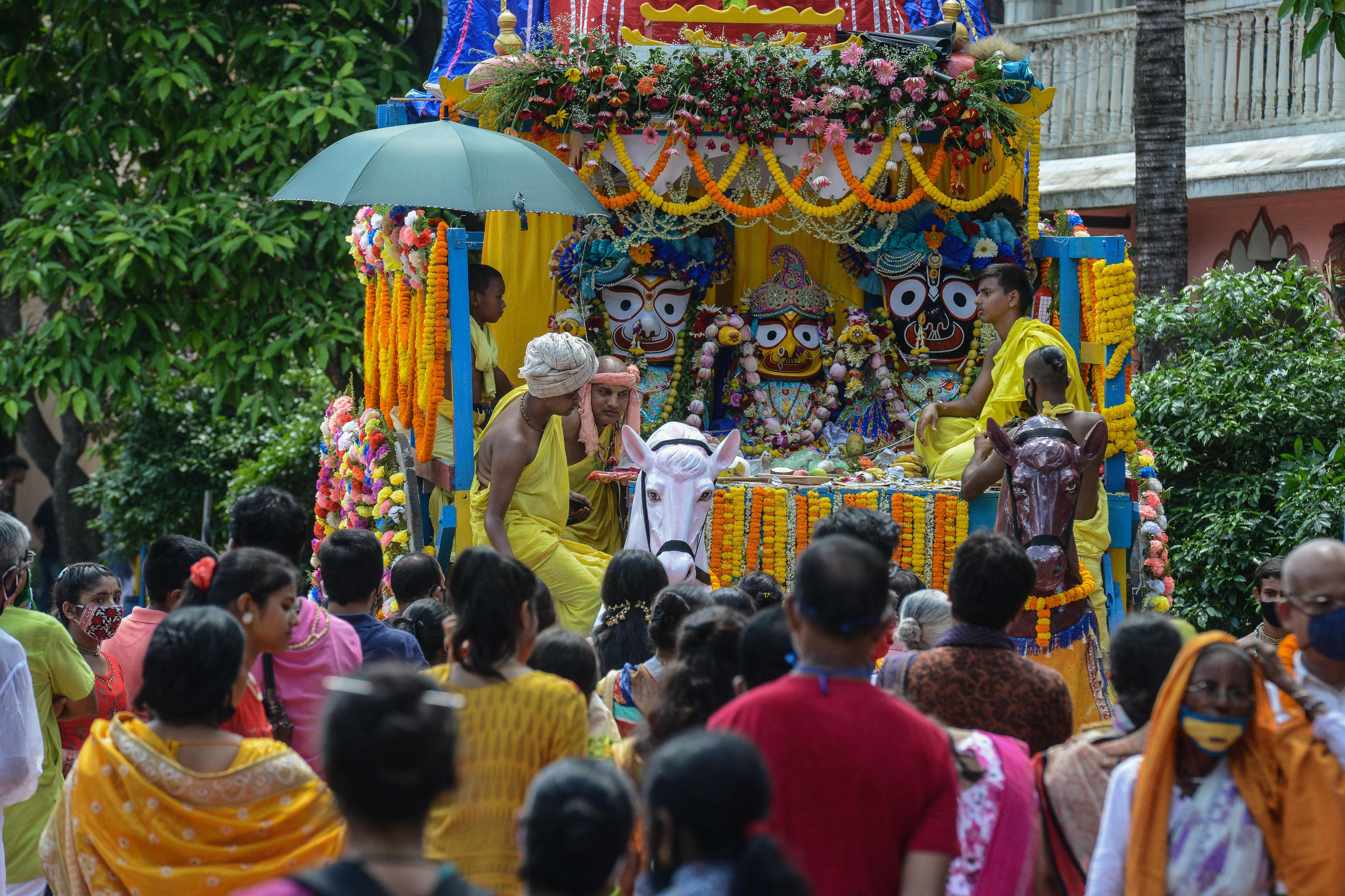 Devotees watch the pulling of a chariot during the annual Lord Jagannath Rath Yatra (procession) after the temple management decided against taking out the procession on the roads in Siliguri city on 12 July 2021
