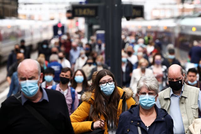 <p>Post-Covid commute: People wearing protective face masks walk along a platform at King's Cross Station</p>