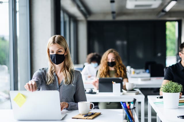 <p>A group of people wearing face masks at work</p>