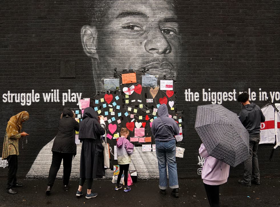 <p>People place messages of support on top of bin liners that were placed over offensive wording on the mural of Manchester United striker and England player Marcus Rashford on the wall of the Coffee House Cafe on Copson Street, Withington</p>
