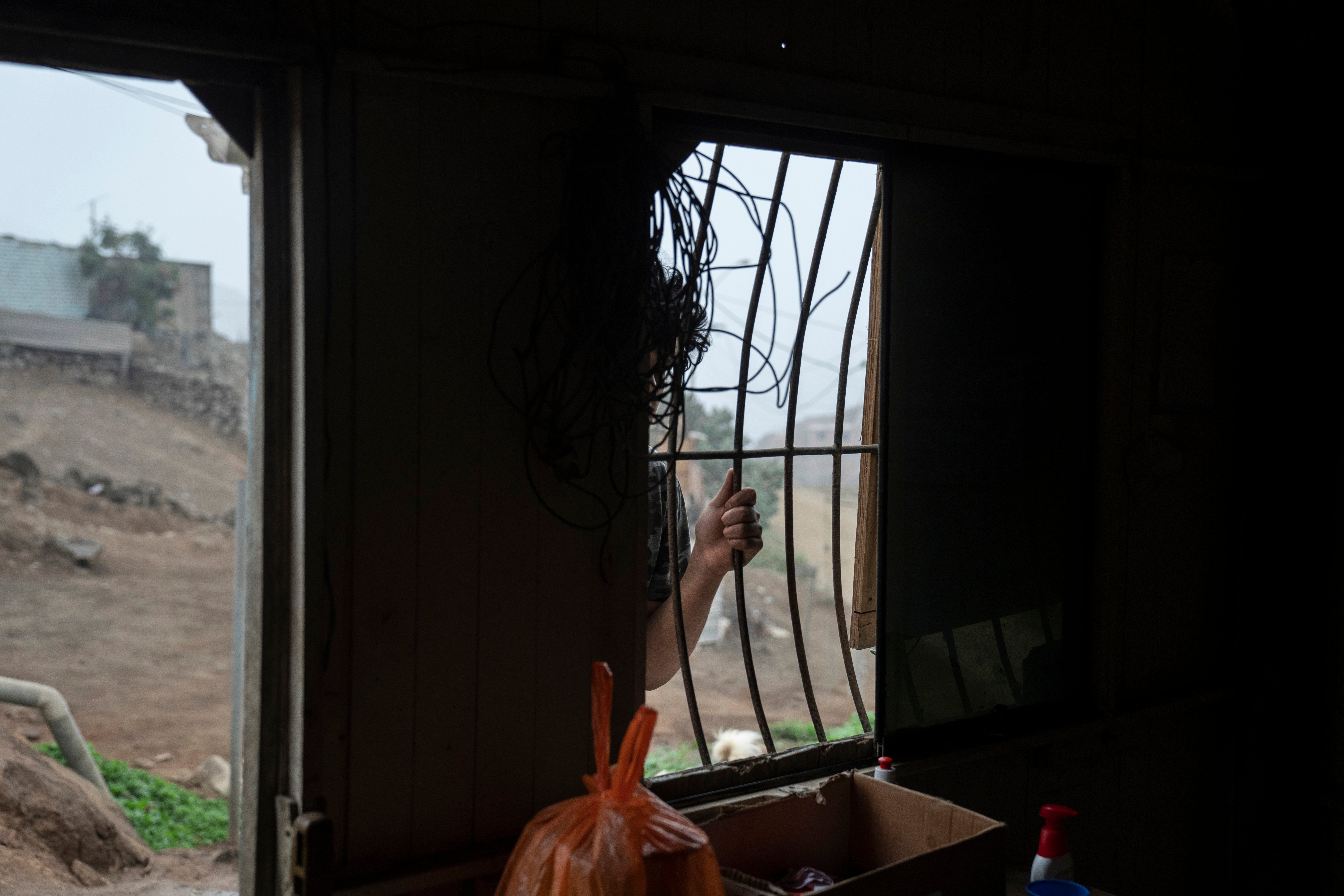 A Peruvian man waits at the window of a communal kitchen in an impoverished neighbourhood in Lima