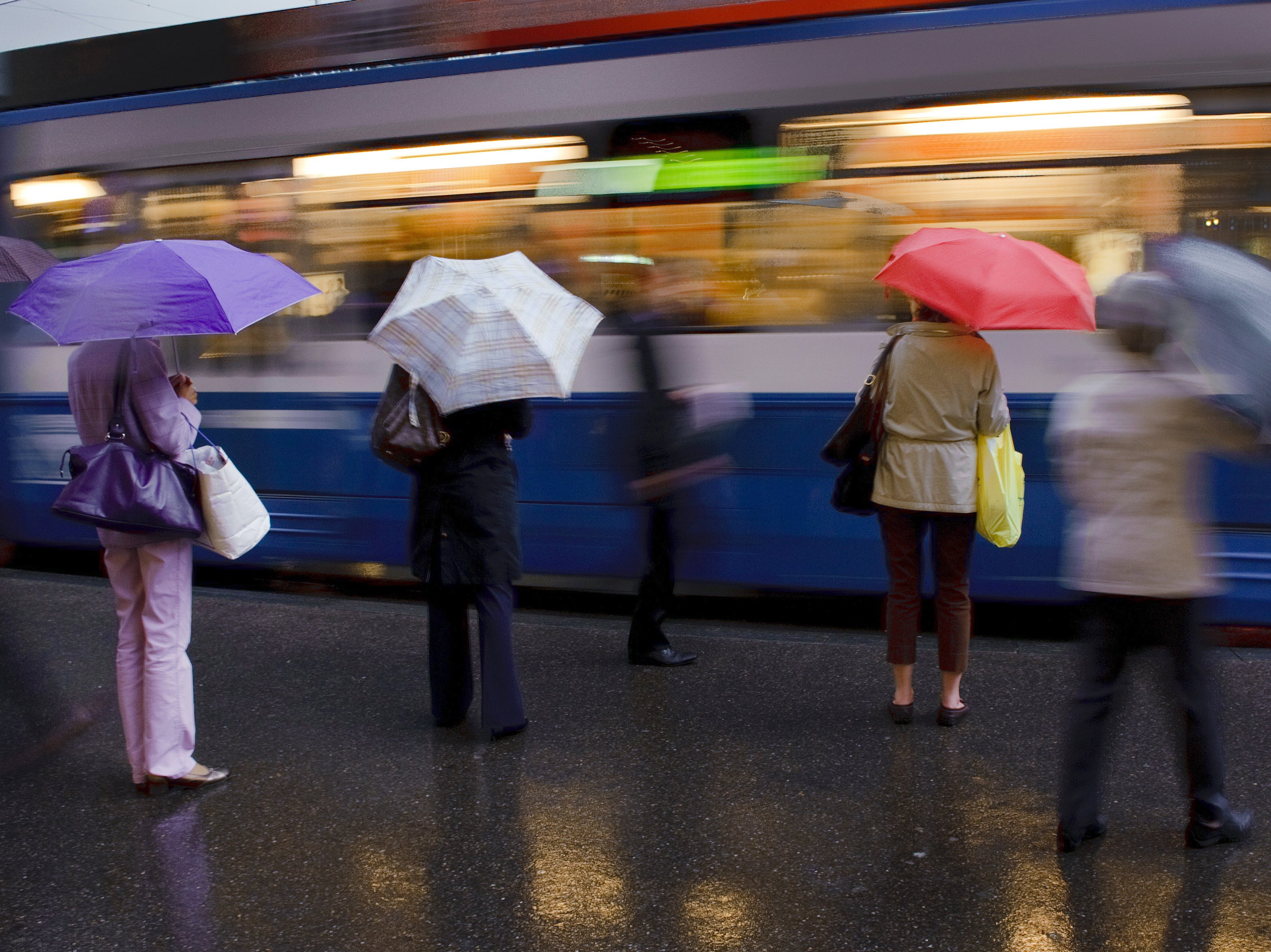 Commuters wait for a tram in the rain in the centre of Zurich