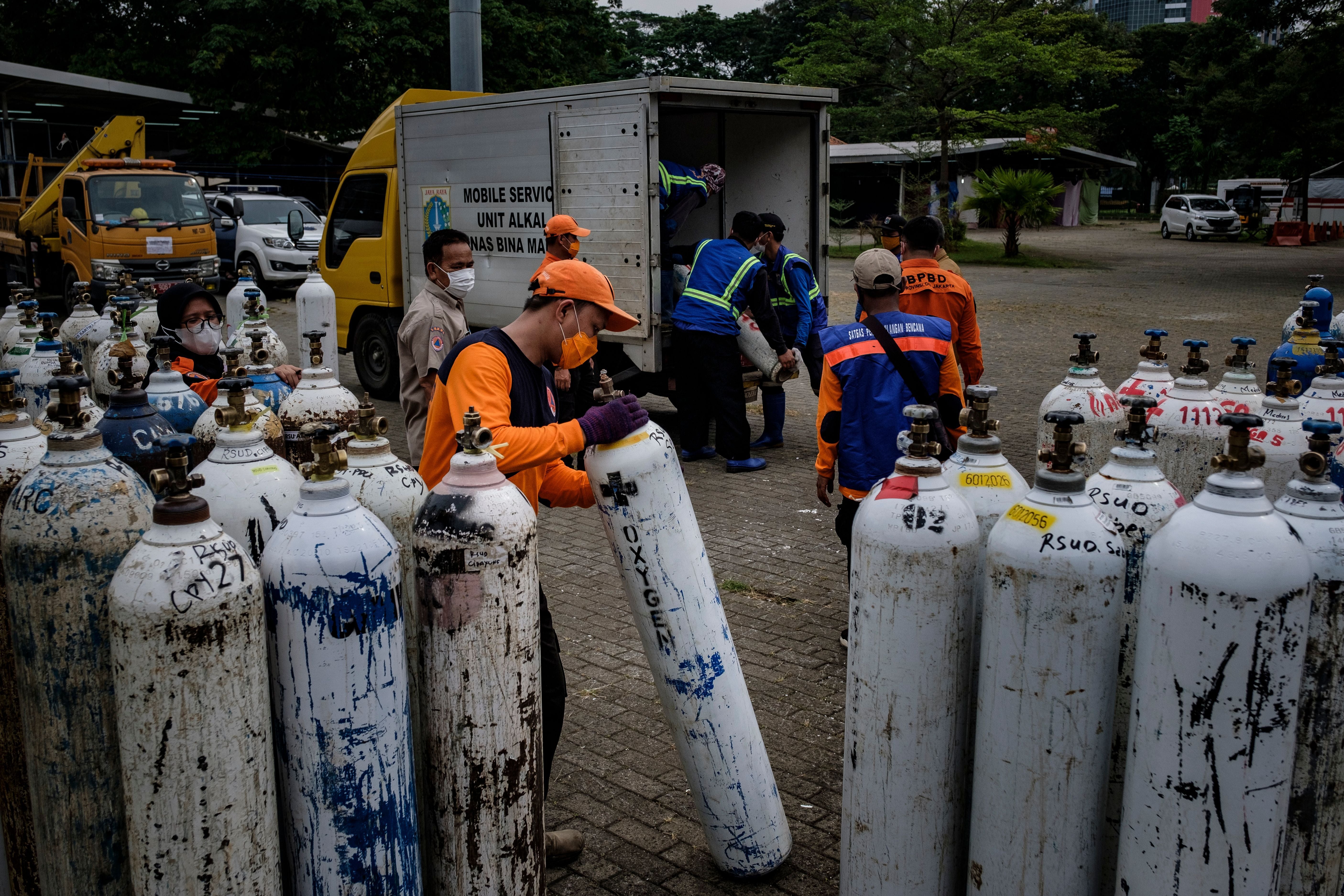 Members of Indonesia’s national rescue organisation offload oxygen tanks to be distributed to hospitals in Jakarta on 13 July 2021