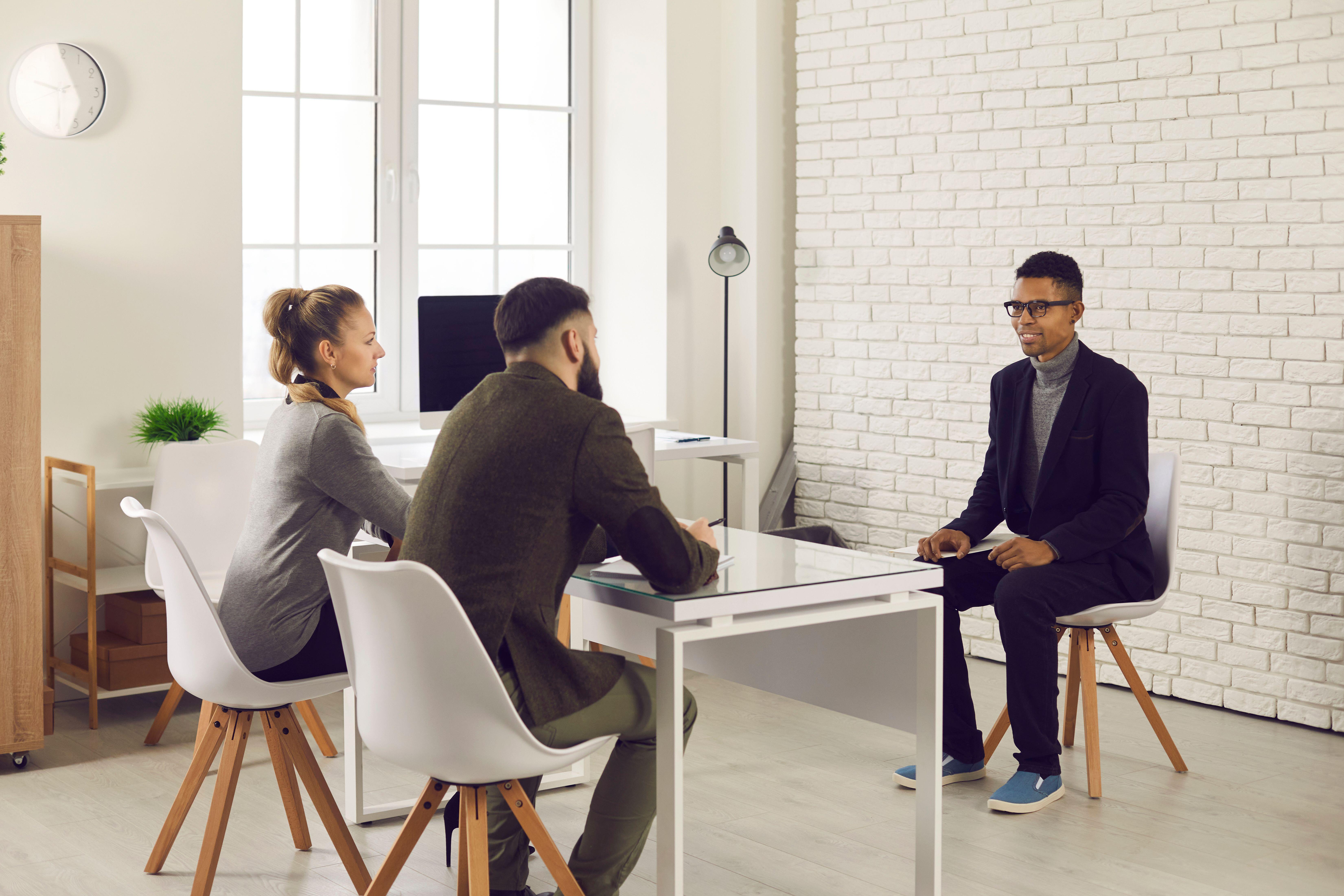 <p>Two HR managers talking to young candidate during job interview</p>