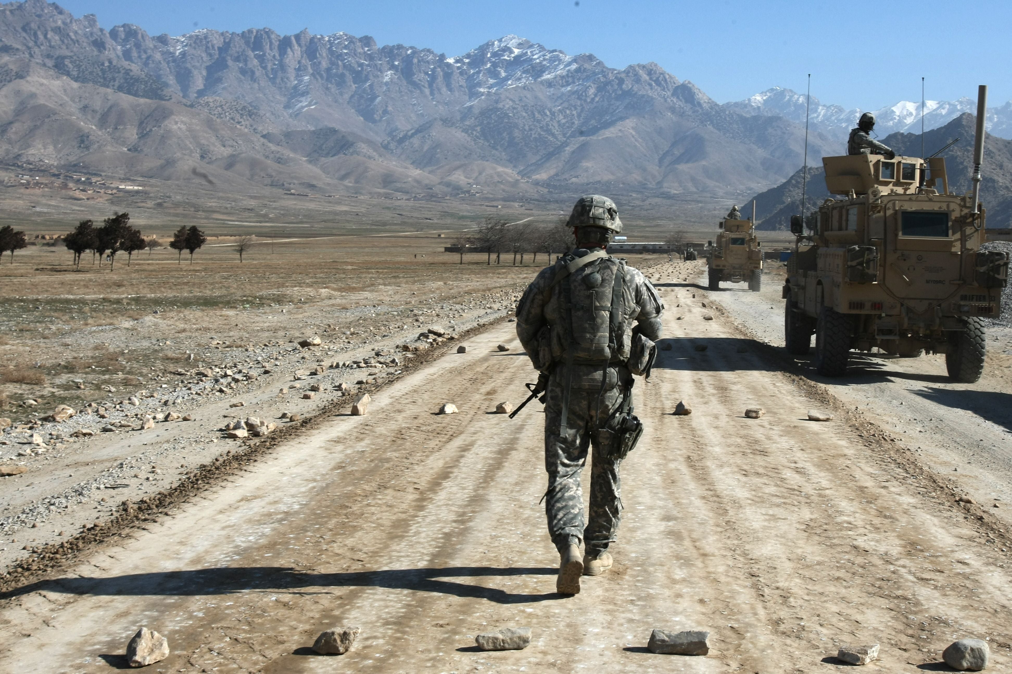A US soldier from a protection squad for a PRT (Provincial Reconstruction Team) walks along a road under construction near Bagram, about 60 km from Kabul in 2010
