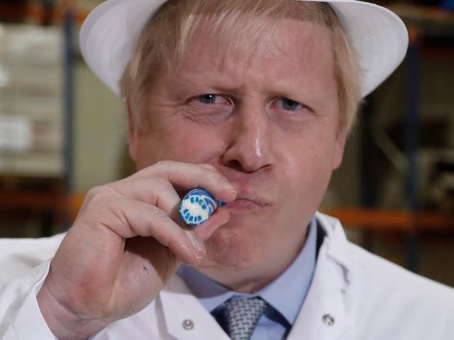 <p>Not so sweet: Boris Johnson eats a stick of rock which reads ‘Back Boris’ during a general election campaign trail stop in Blackpool, November 2019</p>
