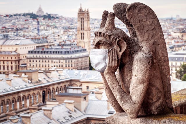 <p>A face maks adorns a gargoyle on Notre Dame in Paris, France</p>