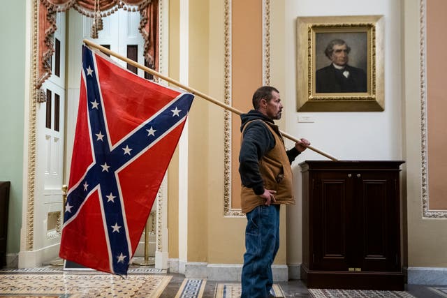 <p>A Trump supporter brings the Confederate Flag into the US Capitol on 6 January</p>