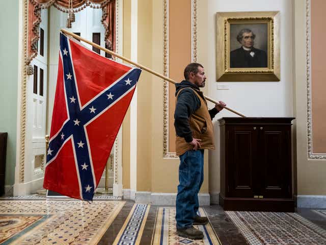 <p>A Trump supporter brings the Confederate Flag into the US Capitol on 6 January</p>