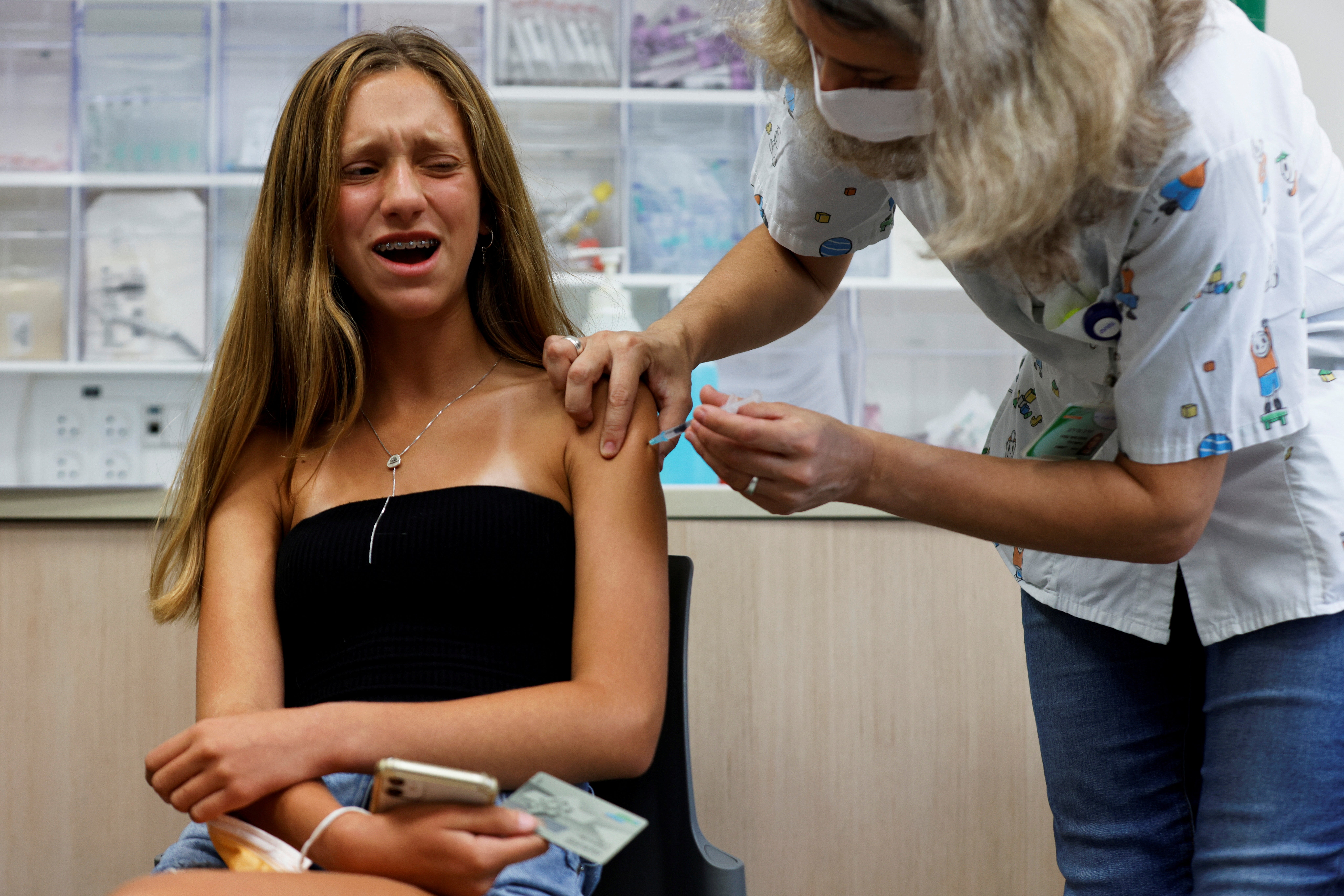 A teenager reacts while receiving a dose of a vaccine against the coronavirus disease (COVID-19) at a Clalit healthcare maintenance organisation in Tel Aviv, Israel