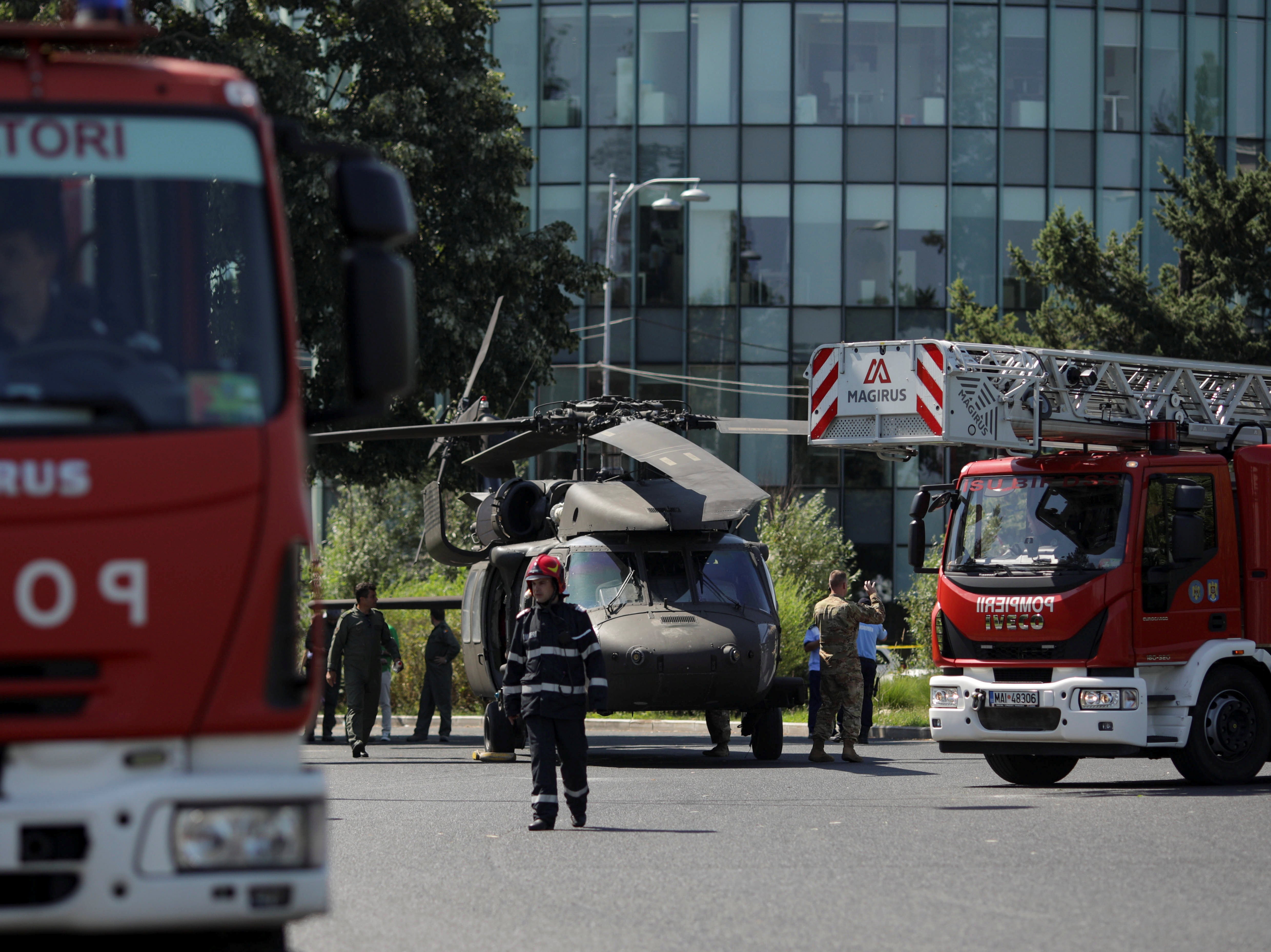 Romanian firefighters are seen near a military Black Hawk helicopter that made an emergency landing in central Bucharest, Romania, July 15, 2021.