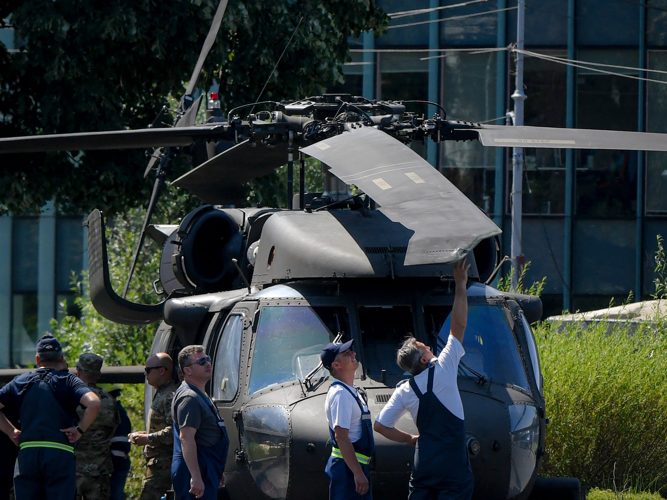 Men inspect the damaged blade of a U.S military Black Hawk helicopter following an emergency landing on a busy boulevard, in Bucharest, Romania, Thursday, July 15, 2021.