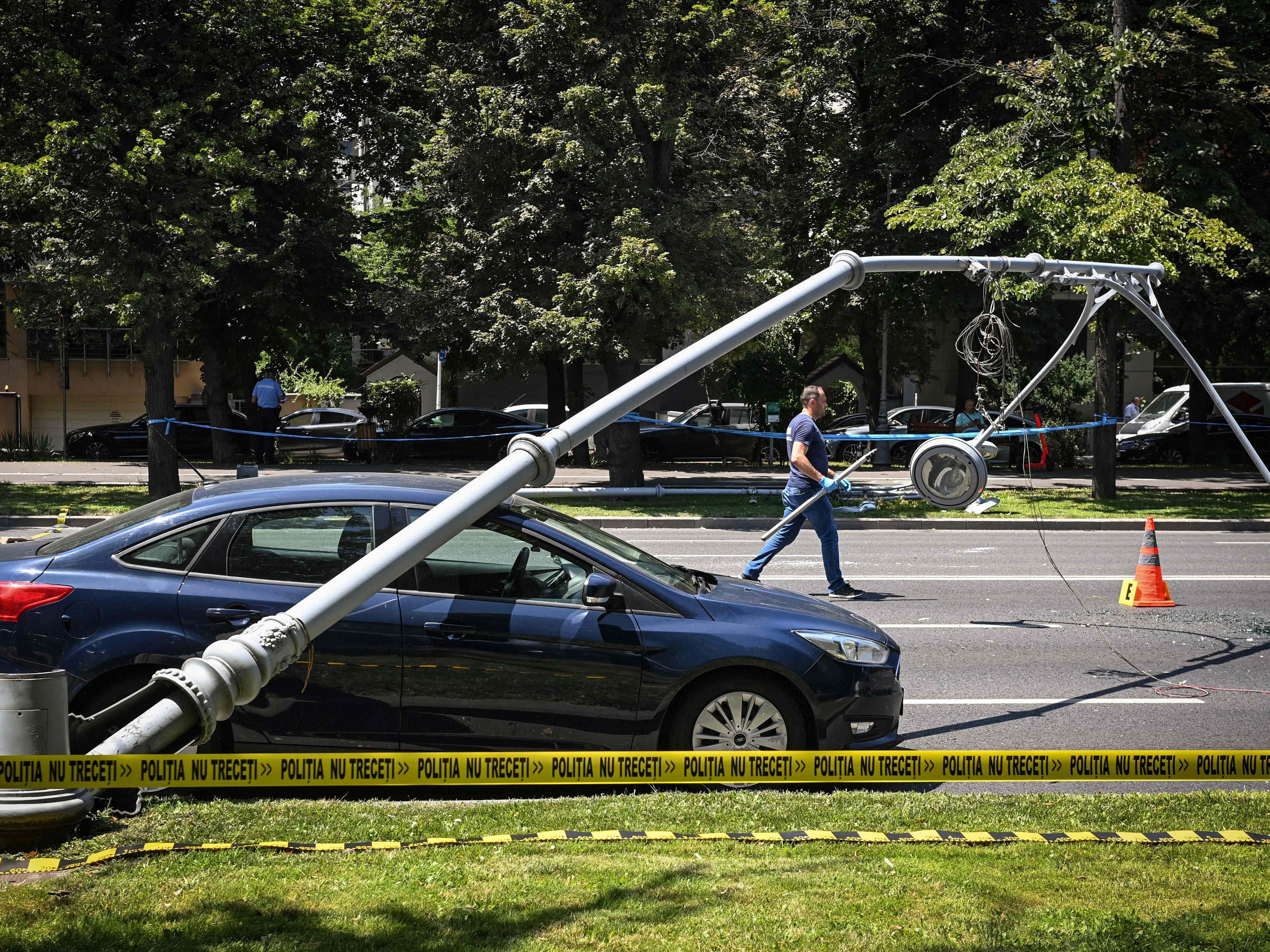 A fallen electric pole on a car is pictured on a boulevard in Bucharest on July 15, 2021, after a Black Hawk helicopter was forced to land.