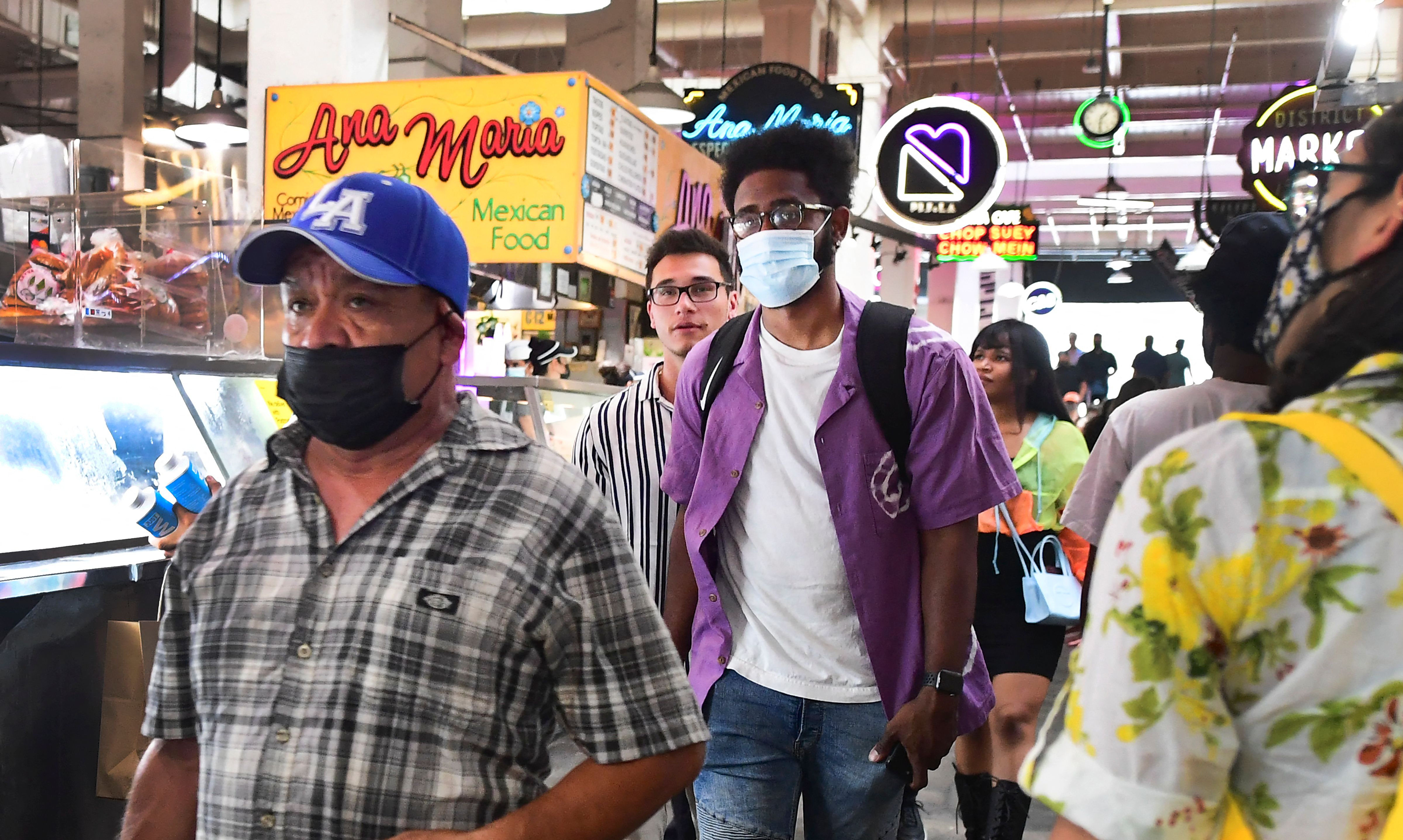 Masked and unmasked people make their way through Grand Central Market in Los Angeles, California on June 29, 2021 as World Health Organization (WHO) urges fully vaccinated people to continue wearing masks with the rapid spread of the Delta variant. - Officials are issuing new mask guidance as Covid-19 cases are spiking in parts of the US, especially in areas with low vaccination rates due to the more contagious Delta variant.