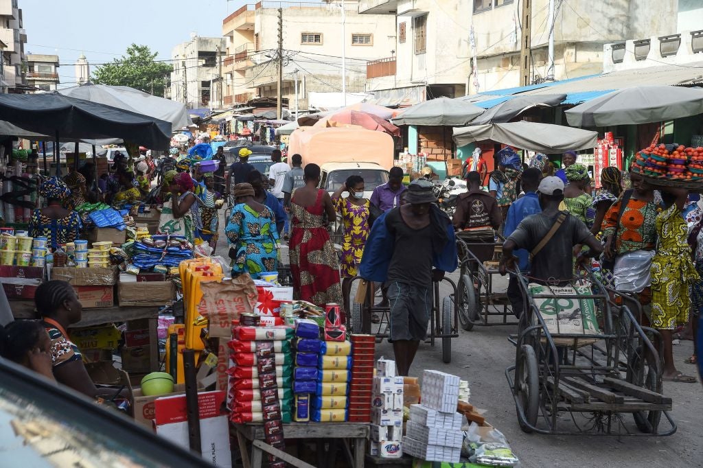 Cart pushers and vendors work in a crowded market in Cotonou, Benin