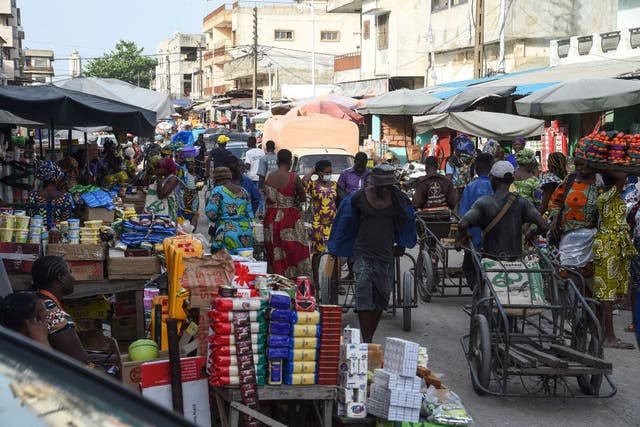 <p>Cart pushers and vendors work in a crowded market in Cotonou, Benin</p>