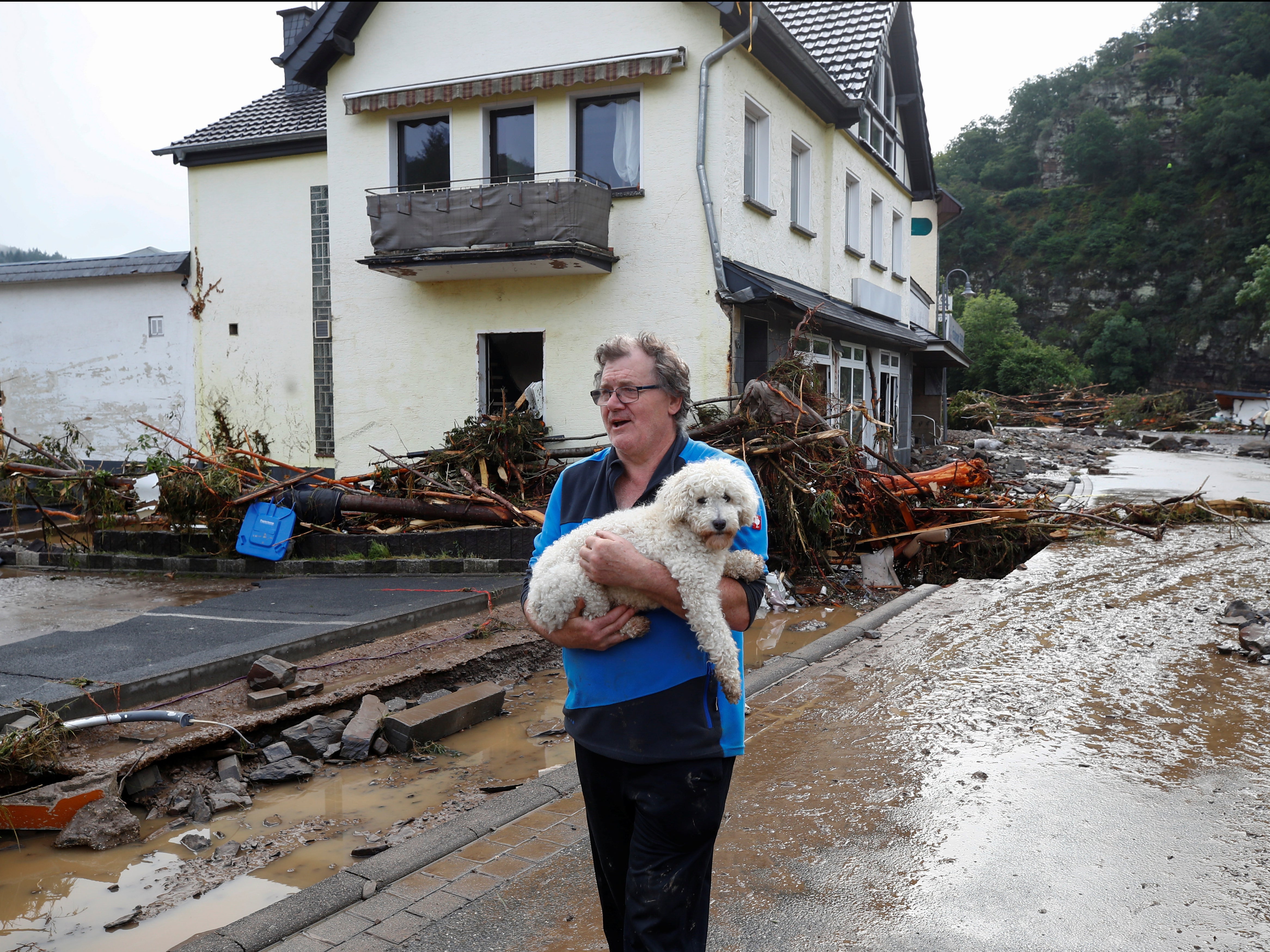 A man carries a dog through the debris brought on by the flooding in Schuld, Germany